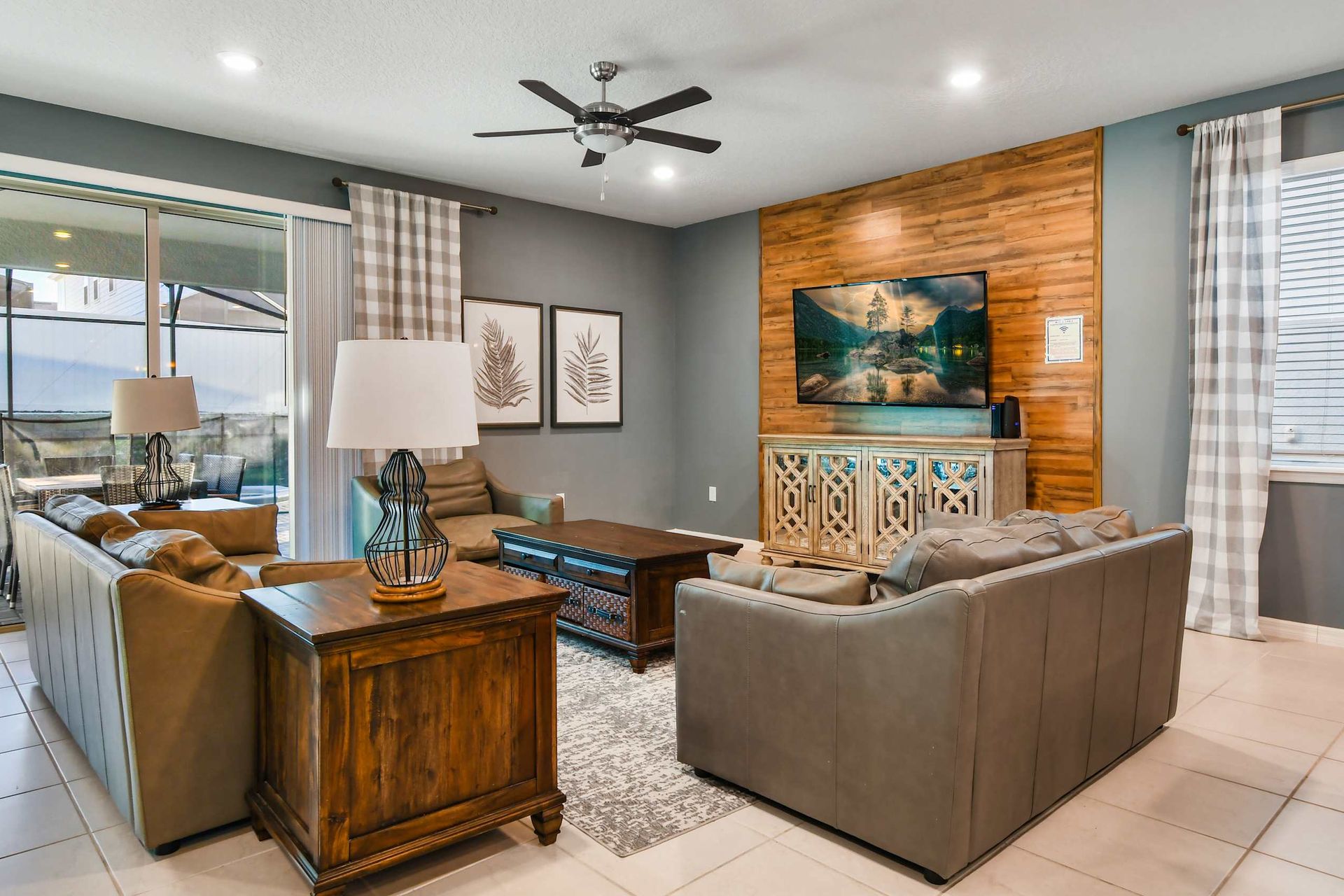 Cozy living area with plush leather seating, rustic accents, large TV, and poolside patio access.