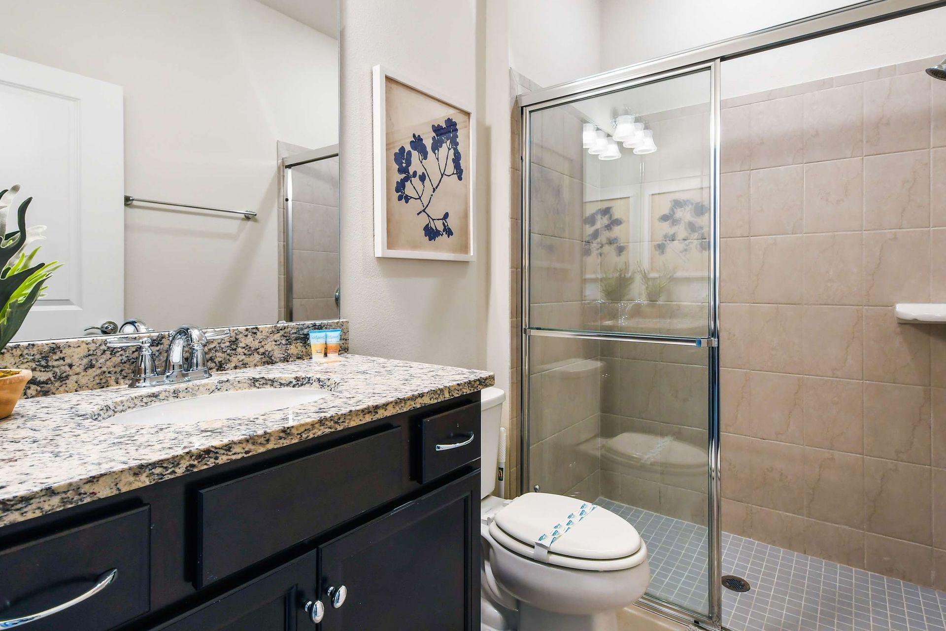 Modern bathroom with granite countertop, walk-in glass shower, and elegant tile details.