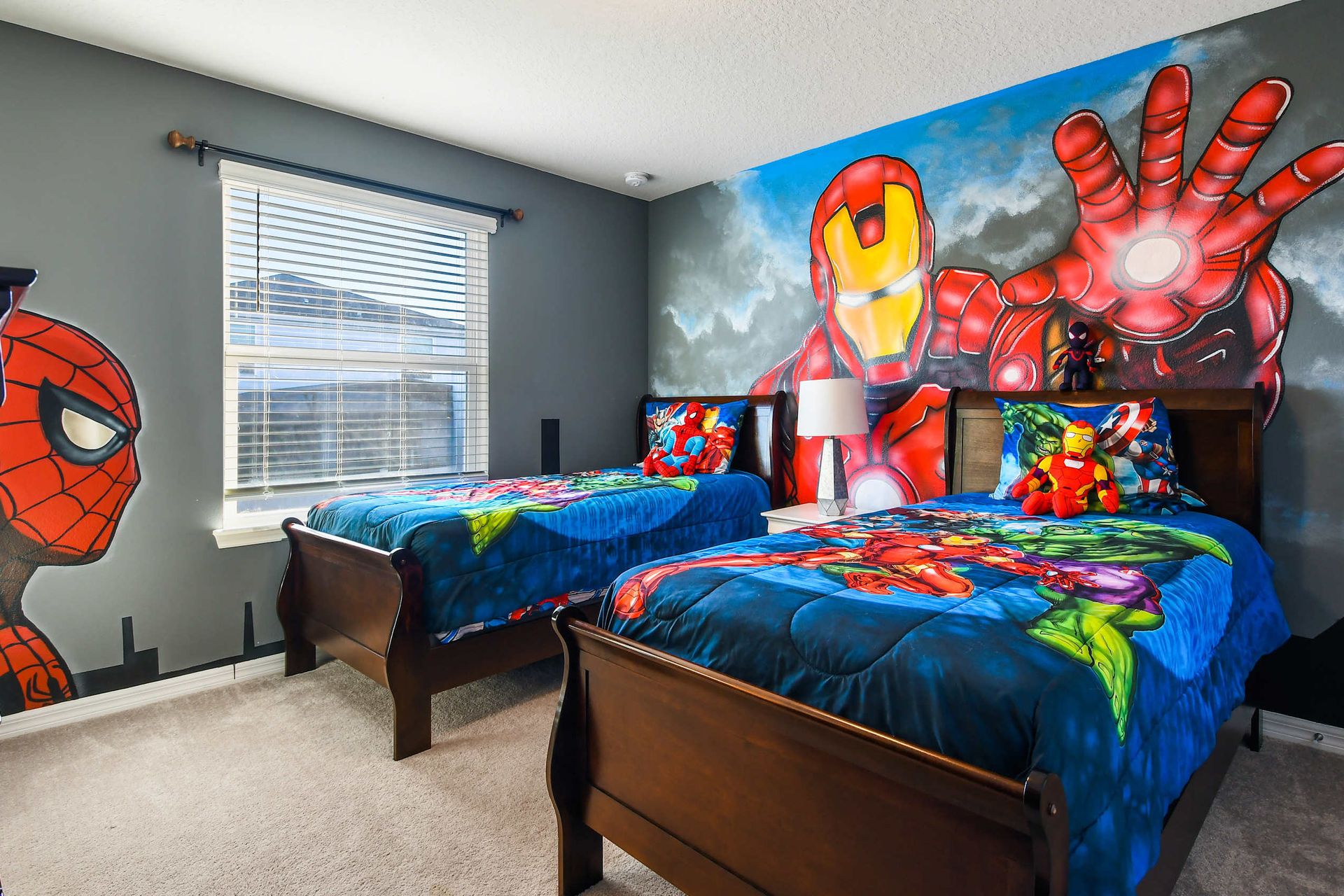 Action-packed superhero bedroom with twin beds, bold murals, and fun Marvel-themed bedding.