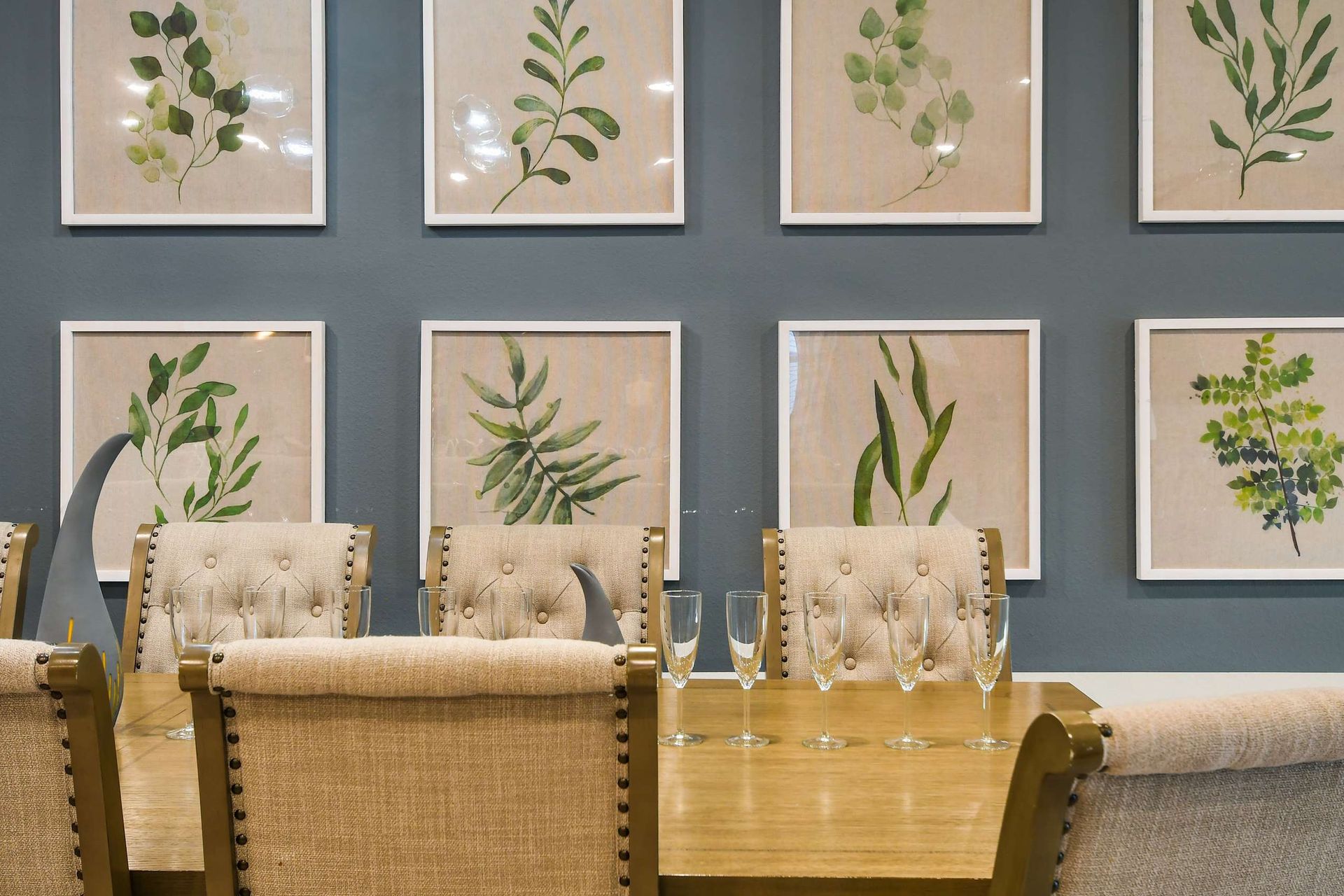 Sophisticated dining setup with tufted chairs, elegant table decor, and framed botanical artwork.
