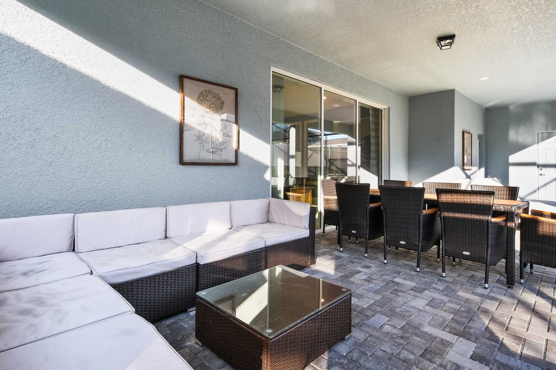 Spacious covered patio with a comfy sectional sofa, coffee table, and large dining area for 8.