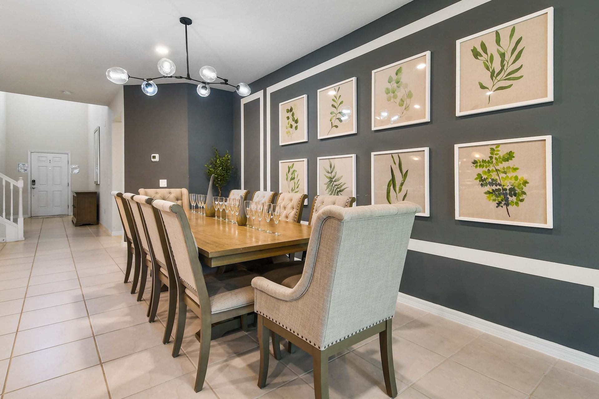 Elegant dining room with a long wooden table, plush seating for 10, and stylish botanical wall art.