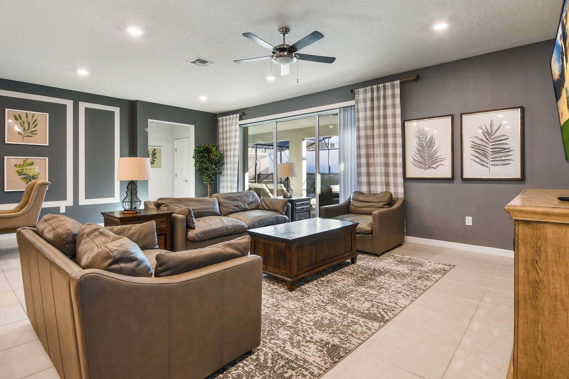 Stylish family room with comfortable leather seating, large TV, and sliding doors to the patio area.