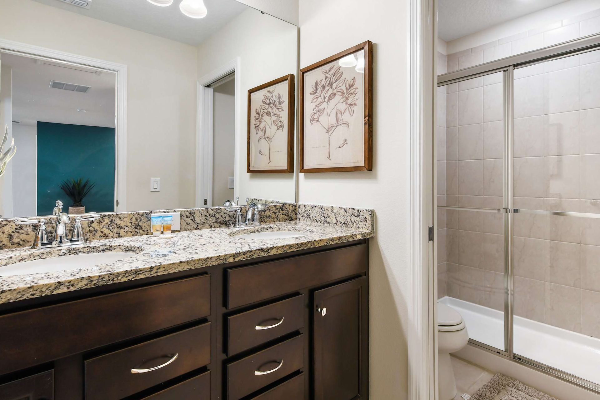 Elegant bathroom with double sinks, granite countertops, and a spacious glass shower.