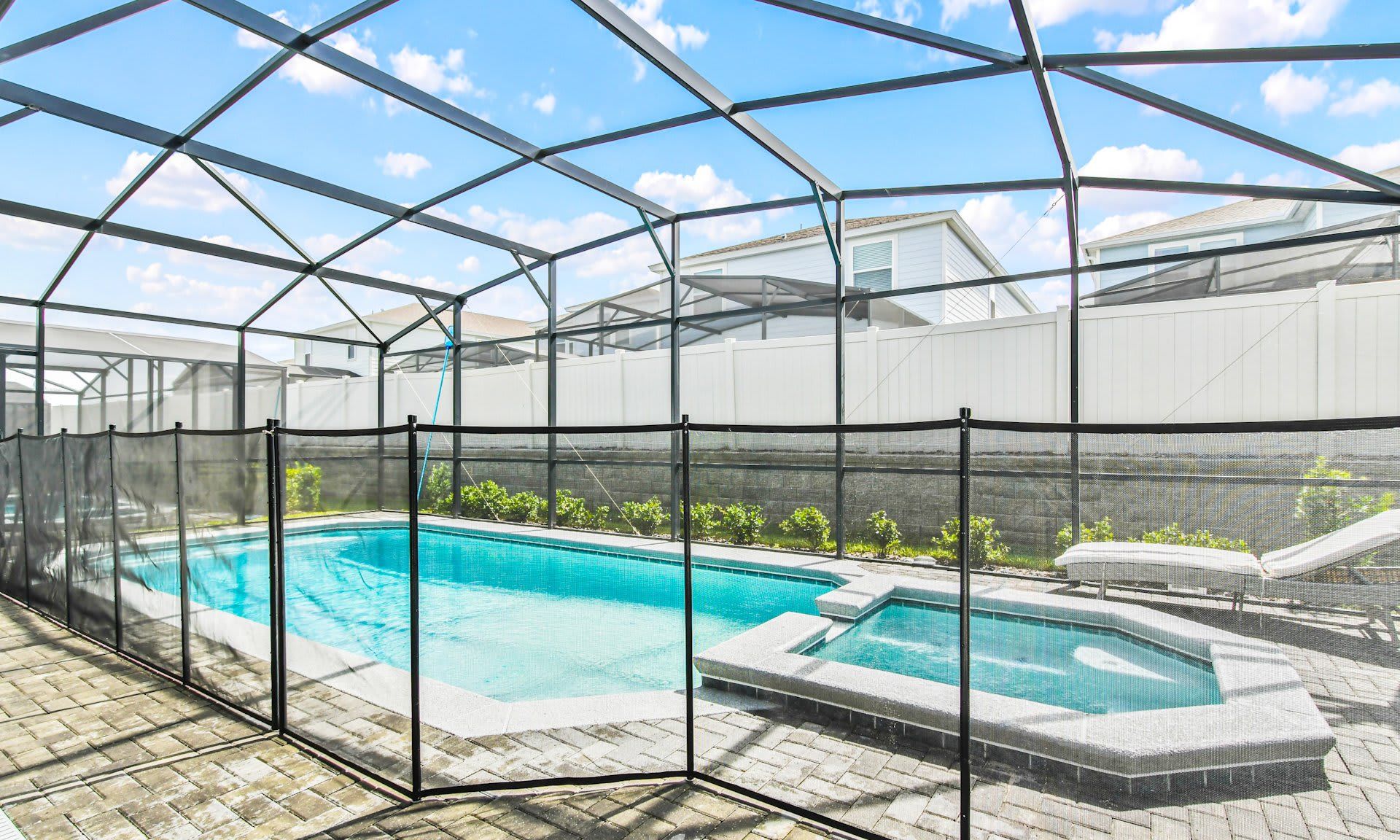 Private screened-in pool and spa area with safety fence, sunny lounging space, and crystal-clear water.