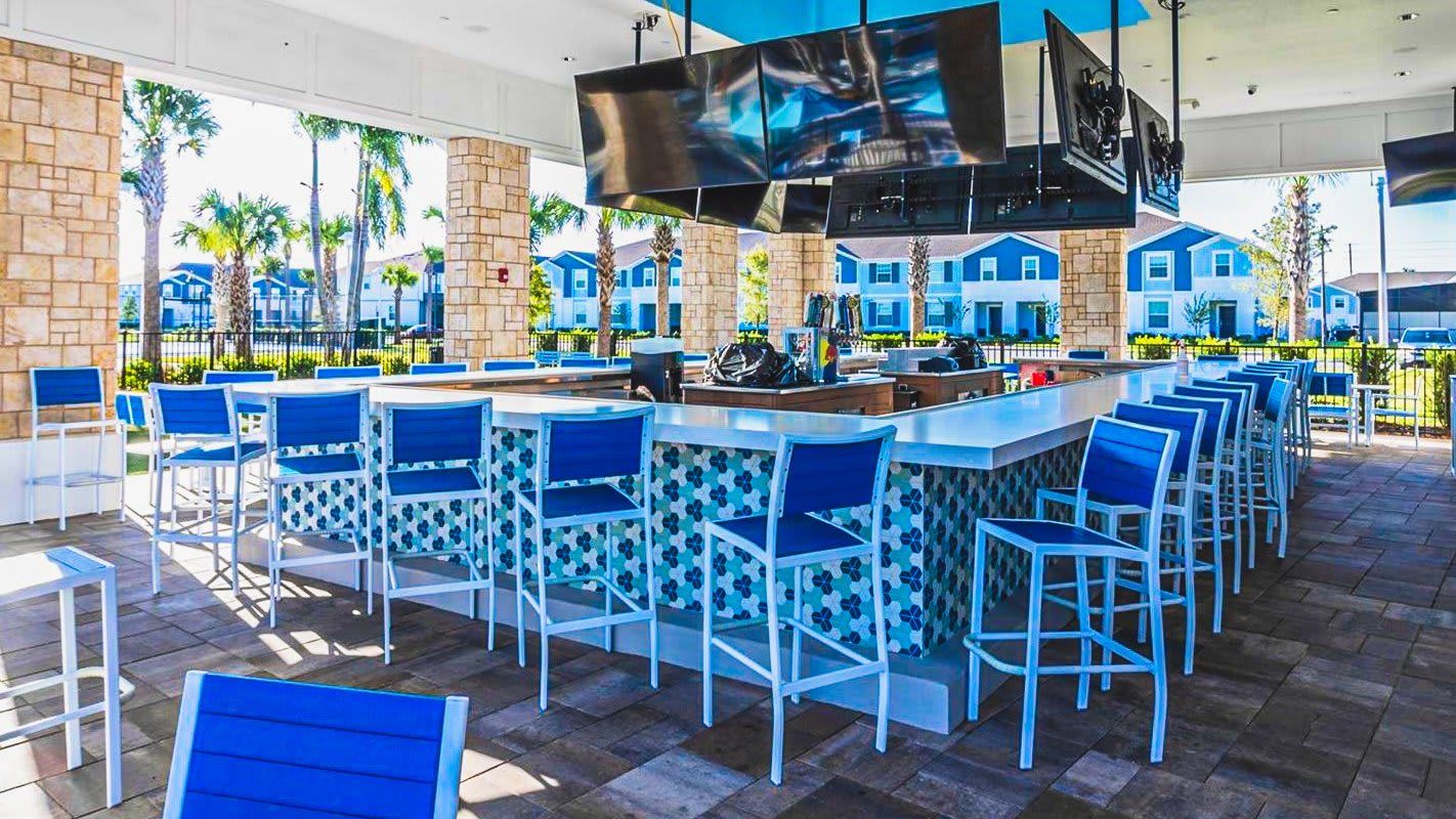 Poolside bar with modern seating and TVs, perfect for refreshing drinks and relaxation.