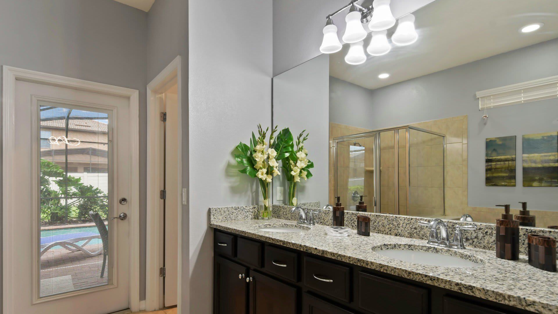 Elegant bathroom with dual sinks, granite counters, walk-in shower & pool access!