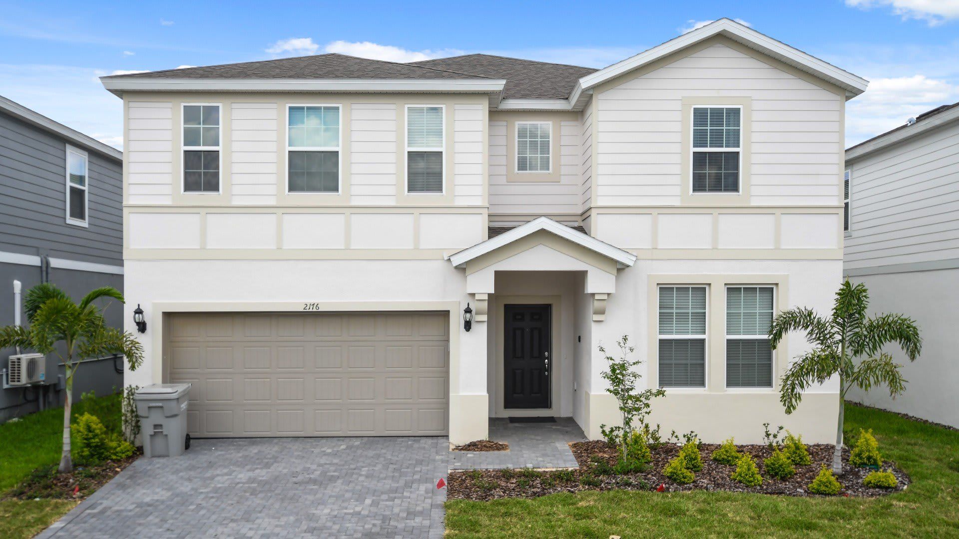 Spacious modern vacation home with a clean exterior, garage, and lush landscaping!
