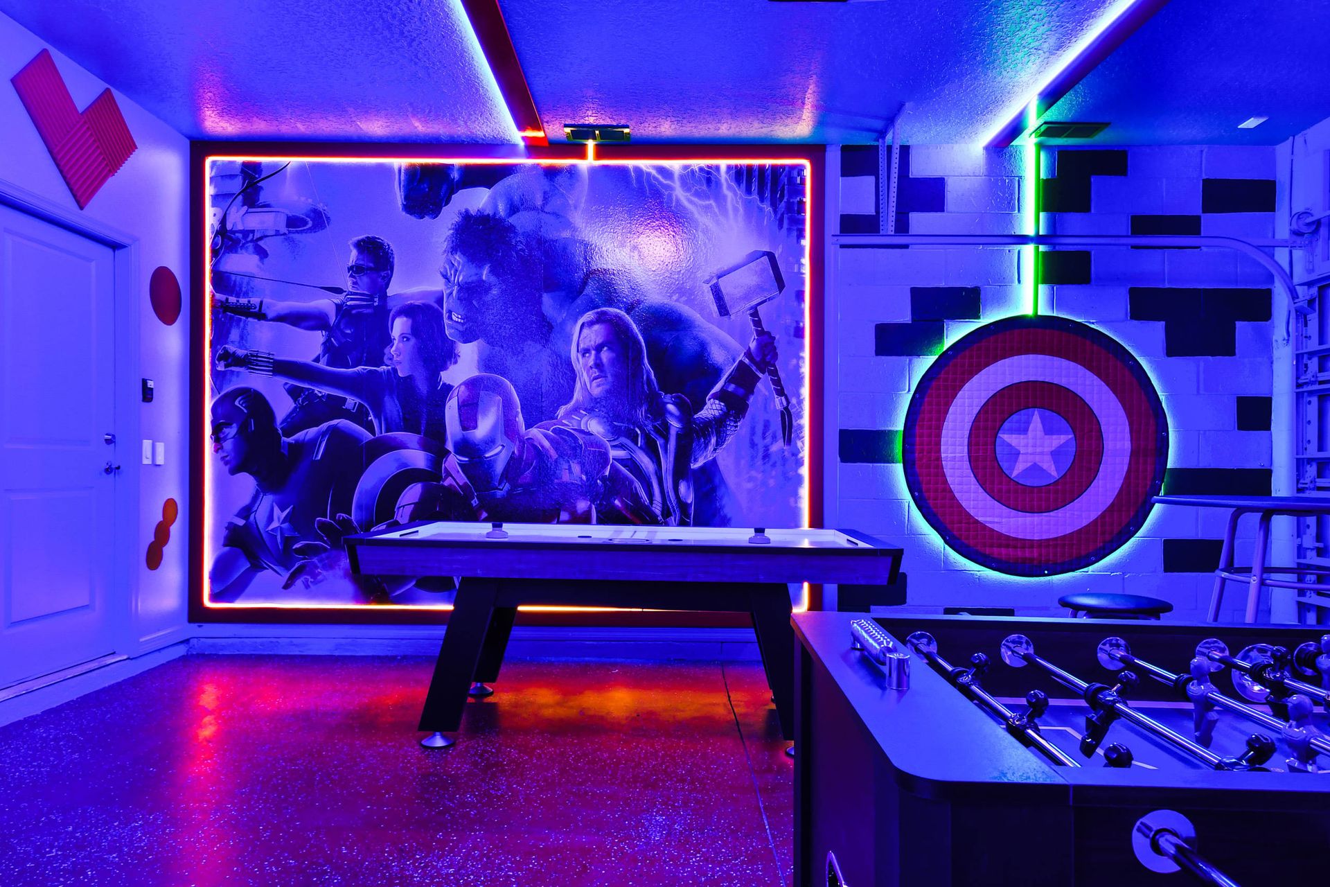Heroic game room featuring neon-lit Avengers art, air hockey, and foosball!