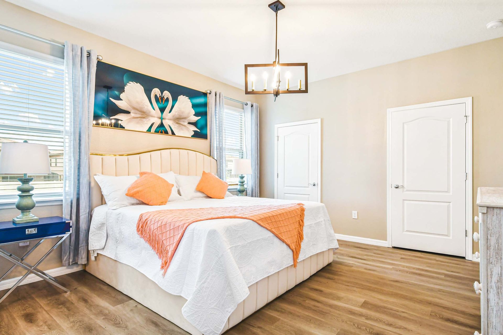 Elegant bedroom with bold orange accents, modern lighting & cozy, luxurious bedding!