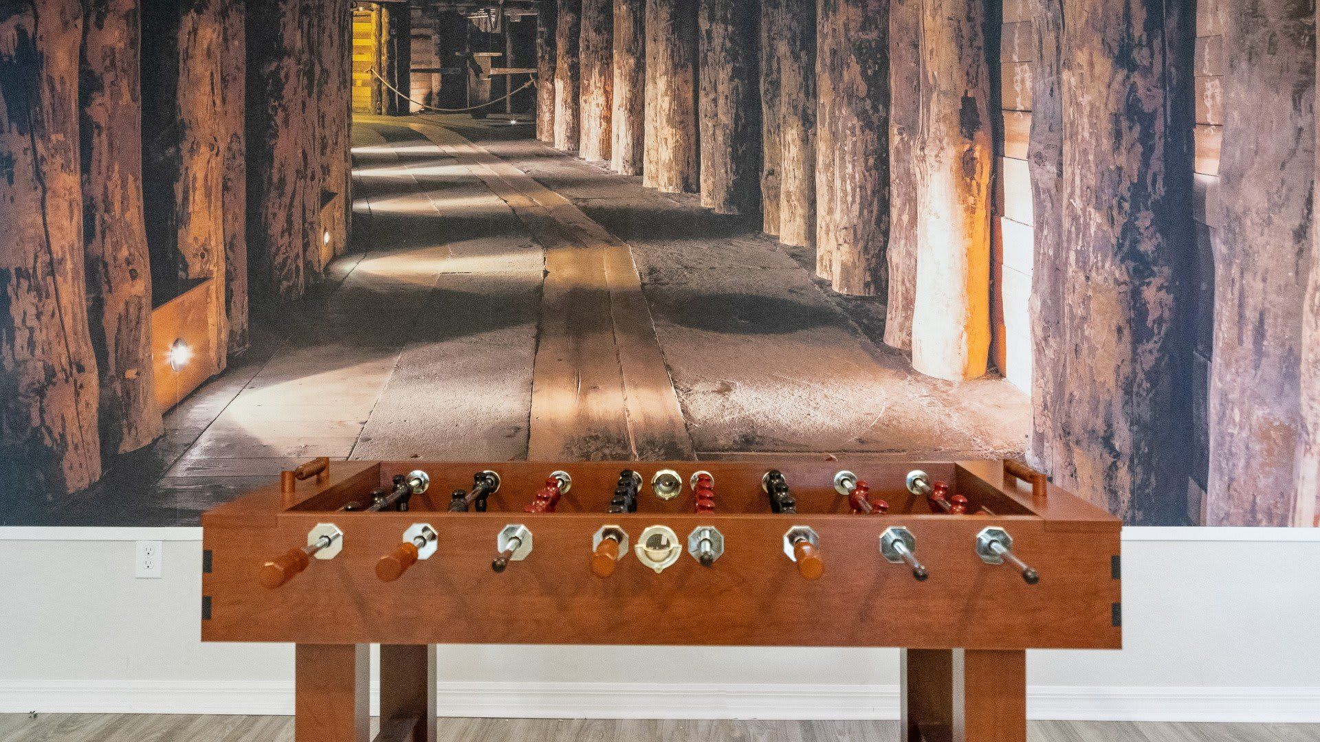 Stylish game room with a foosball table and an immersive rustic tunnel mural!