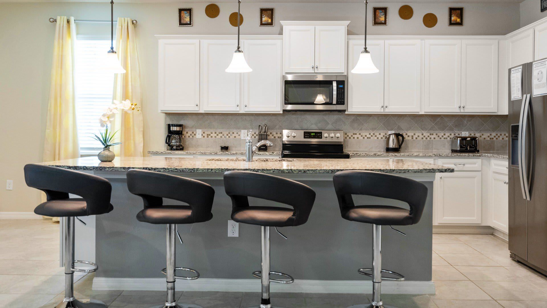 Modern kitchen with sleek granite counters, bar seating, and stainless appliances!