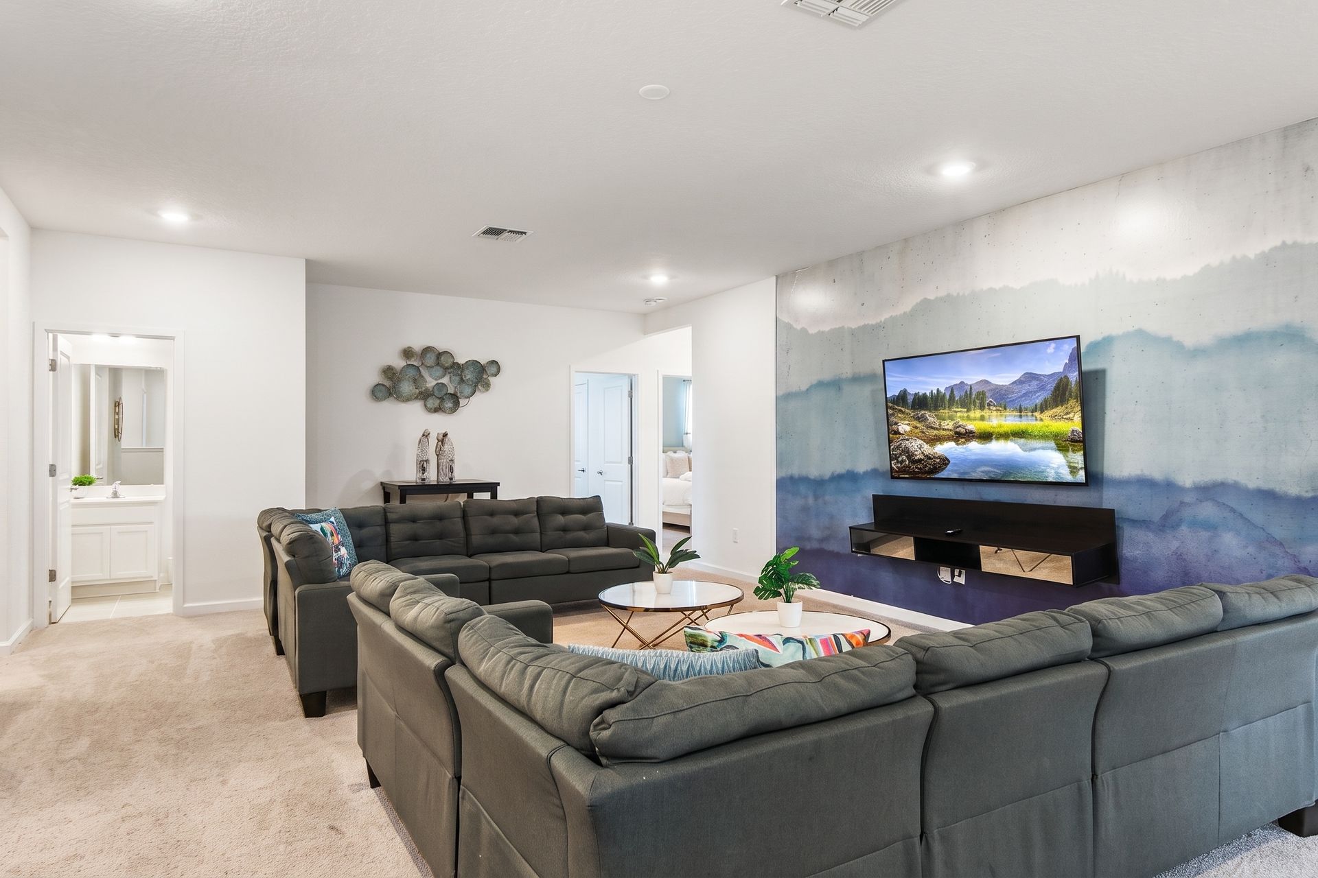 Stylish upstairs lounge with plush seating, a scenic accent wall, and a cozy vibe!