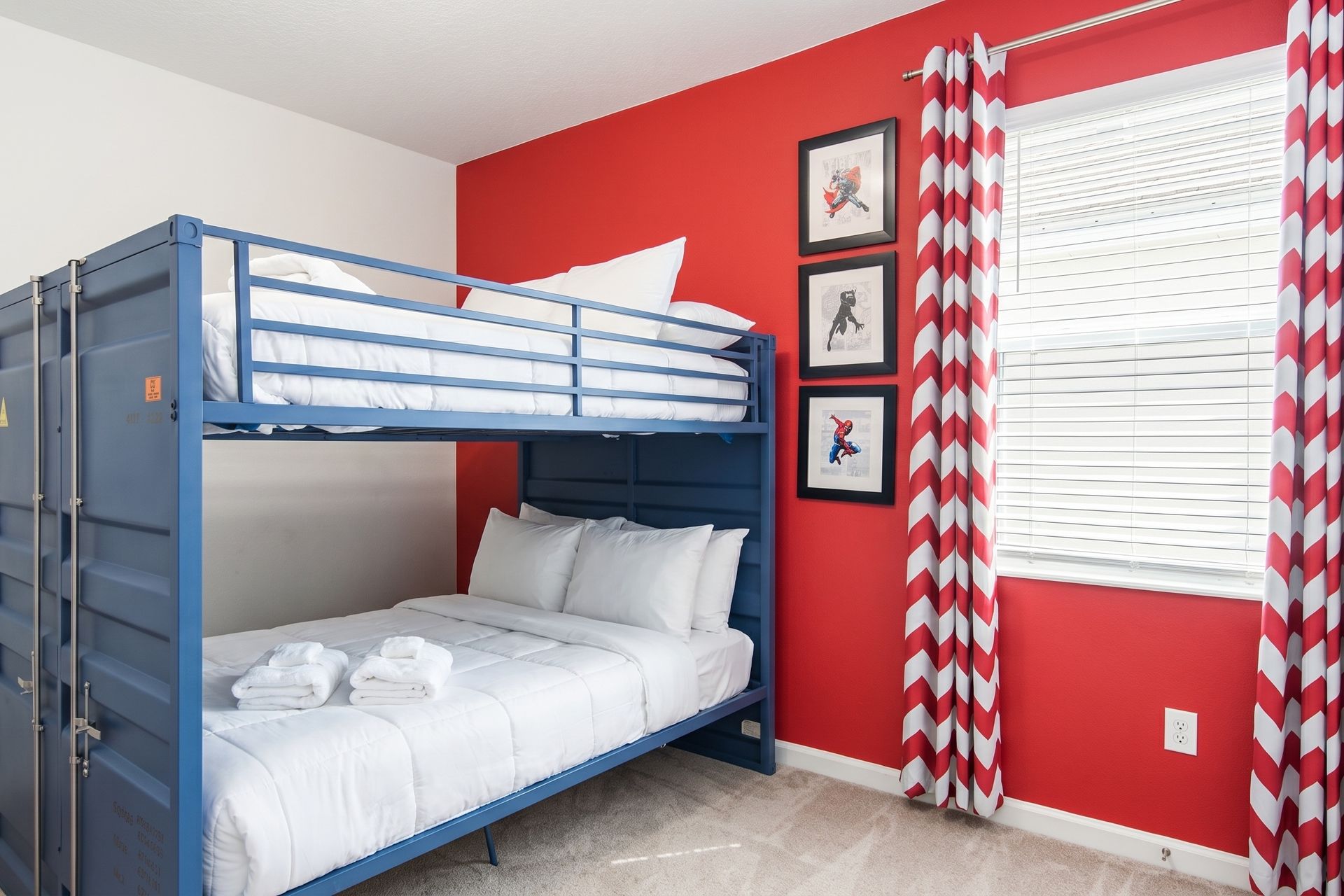 A superhero-themed kids' bedroom featuring a bold red accent wall