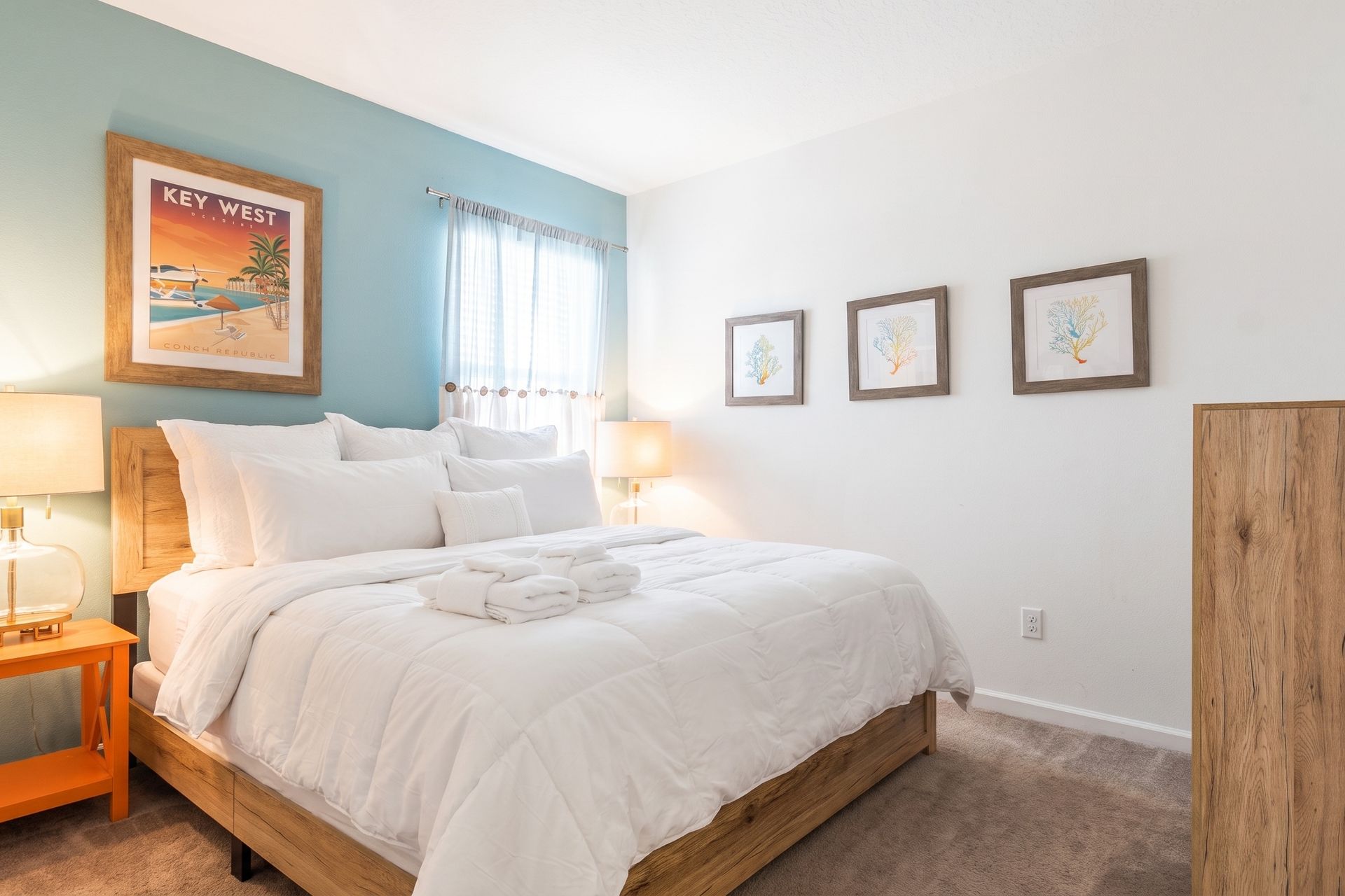 This cozy bedroom embraces a Key West coastal theme, featuring a soft blue-green accent wall