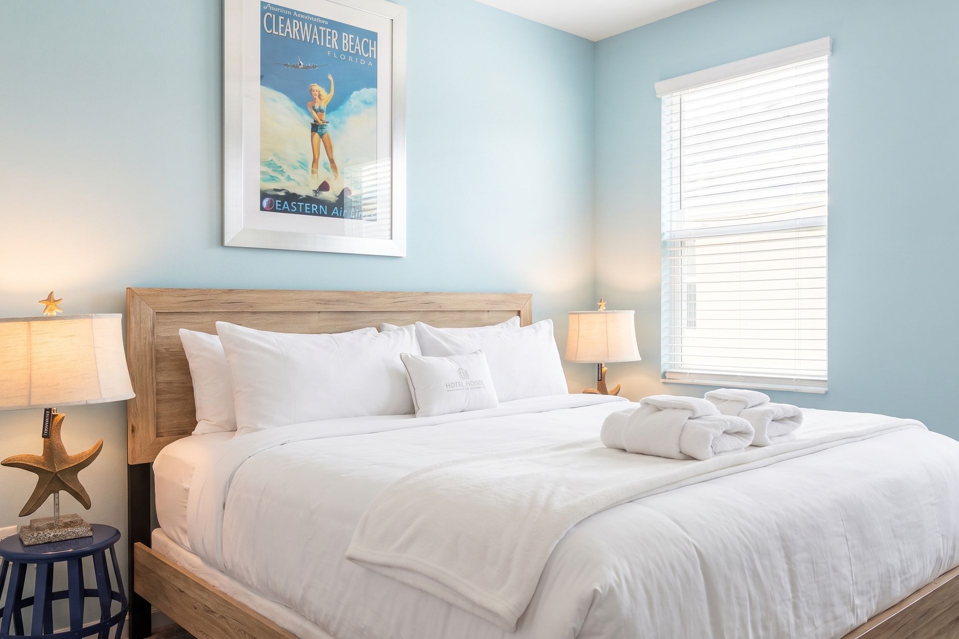 A beautifully decorated coastal-themed bedroom featuring a soft blue accent wall