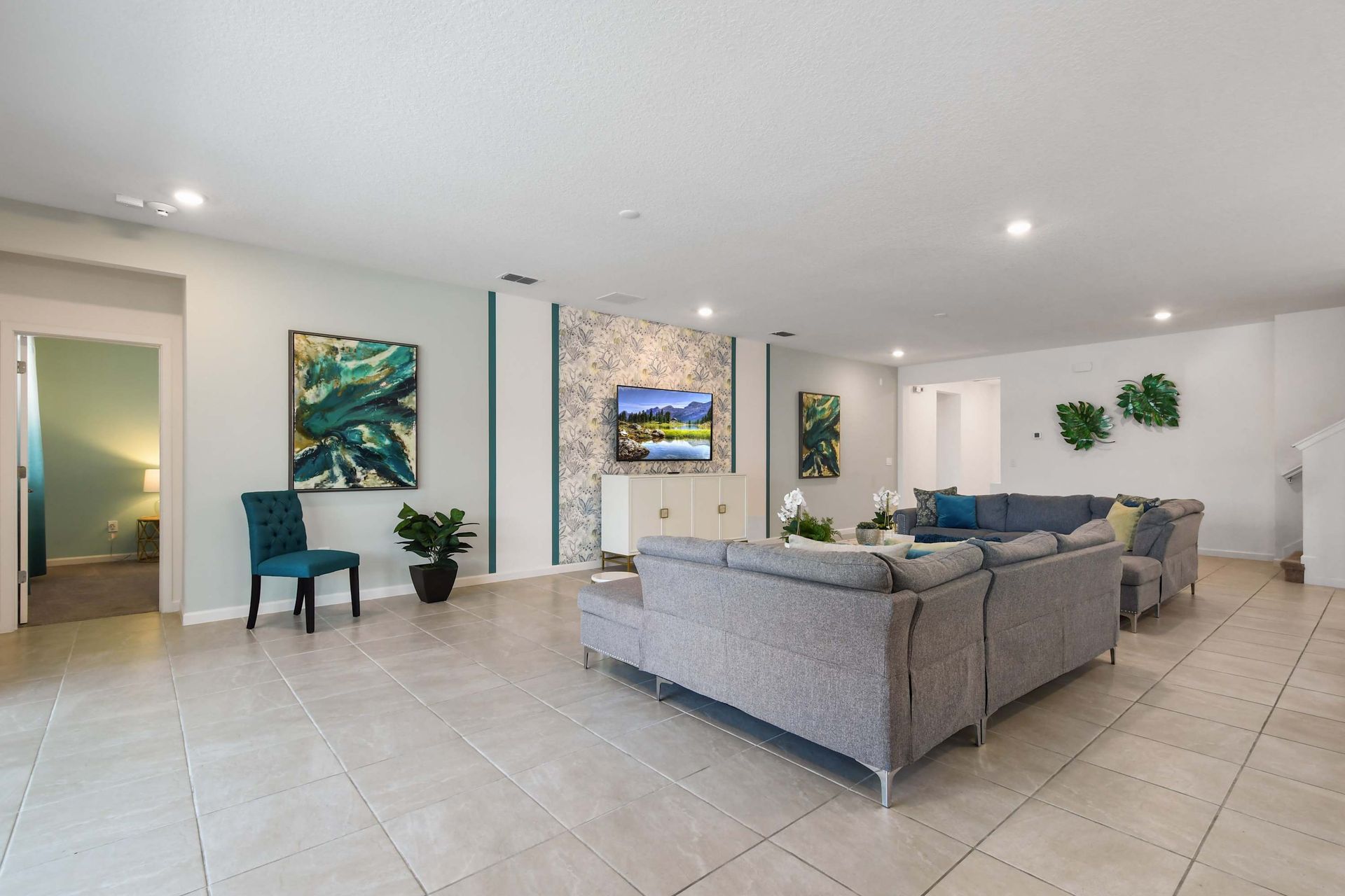 A cozy, open-concept living room featuring a large sectional sofa, contemporary decor, and a wall-mounted TV, idea for relaxation and entertainment.