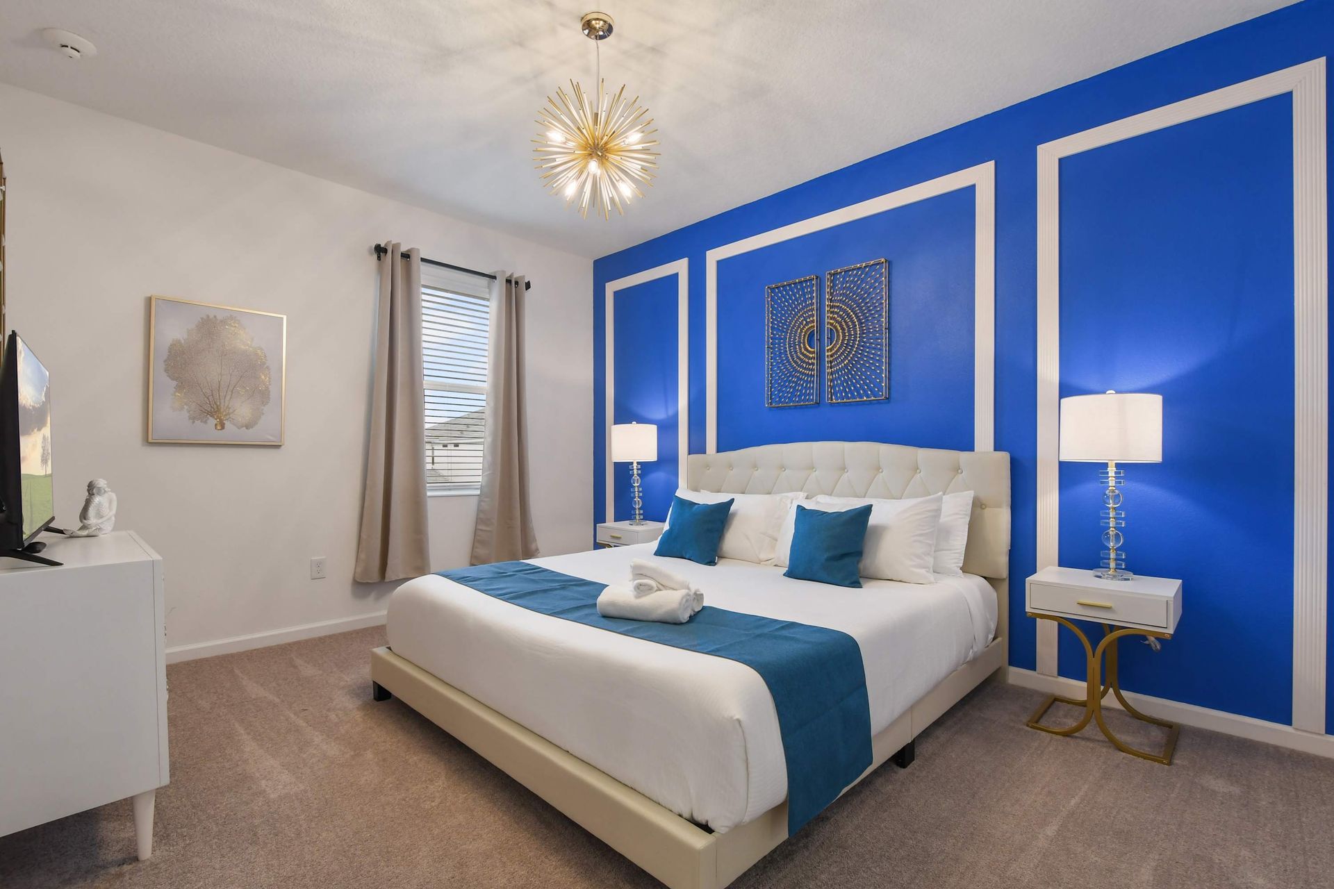 Elegant bedroom with bold blue accent wall, luxurious decor, and a plush king bed.