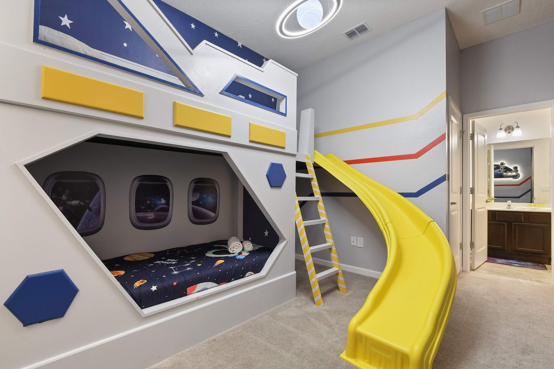 Space-themed kids' bedroom with a custom bunk bed, slide, and galactic decor.