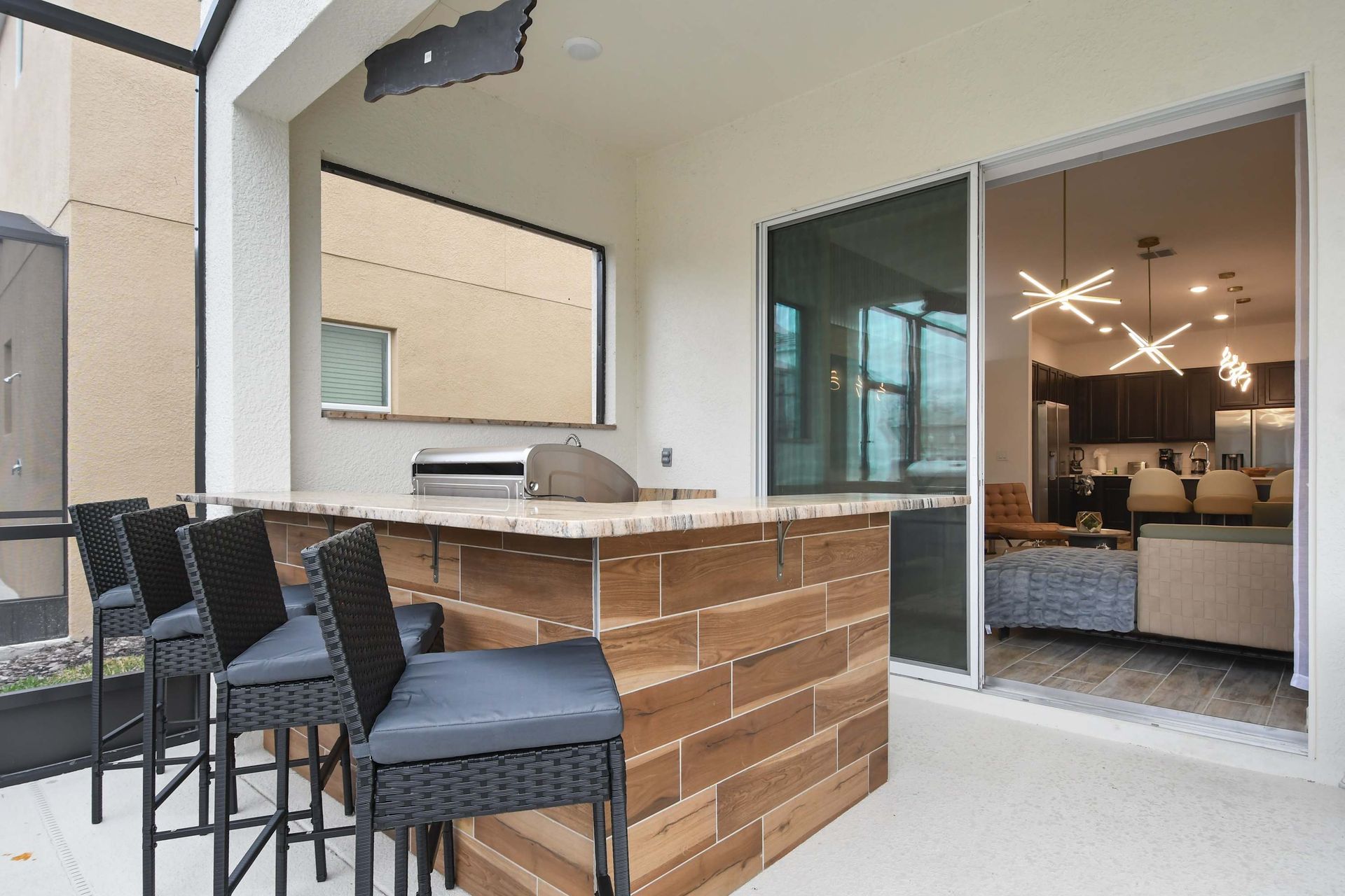 Stylish outdoor bar with built-in grill, cozy seating, and seamless indoor-outdoor flow.