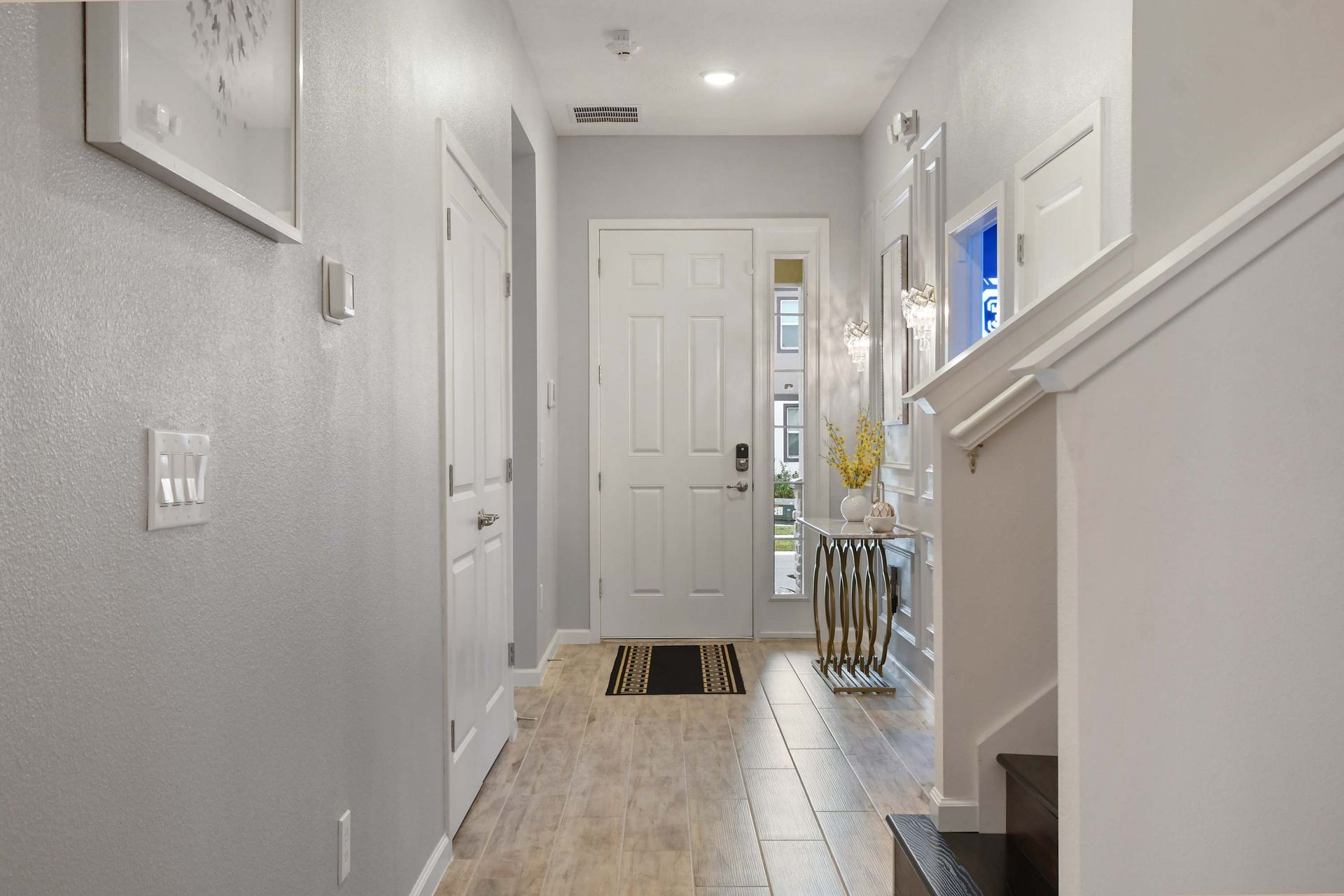 A stylish and welcoming entryway featuring elegant decor, modern lighting, and a sleek console table with a decorative vase.
