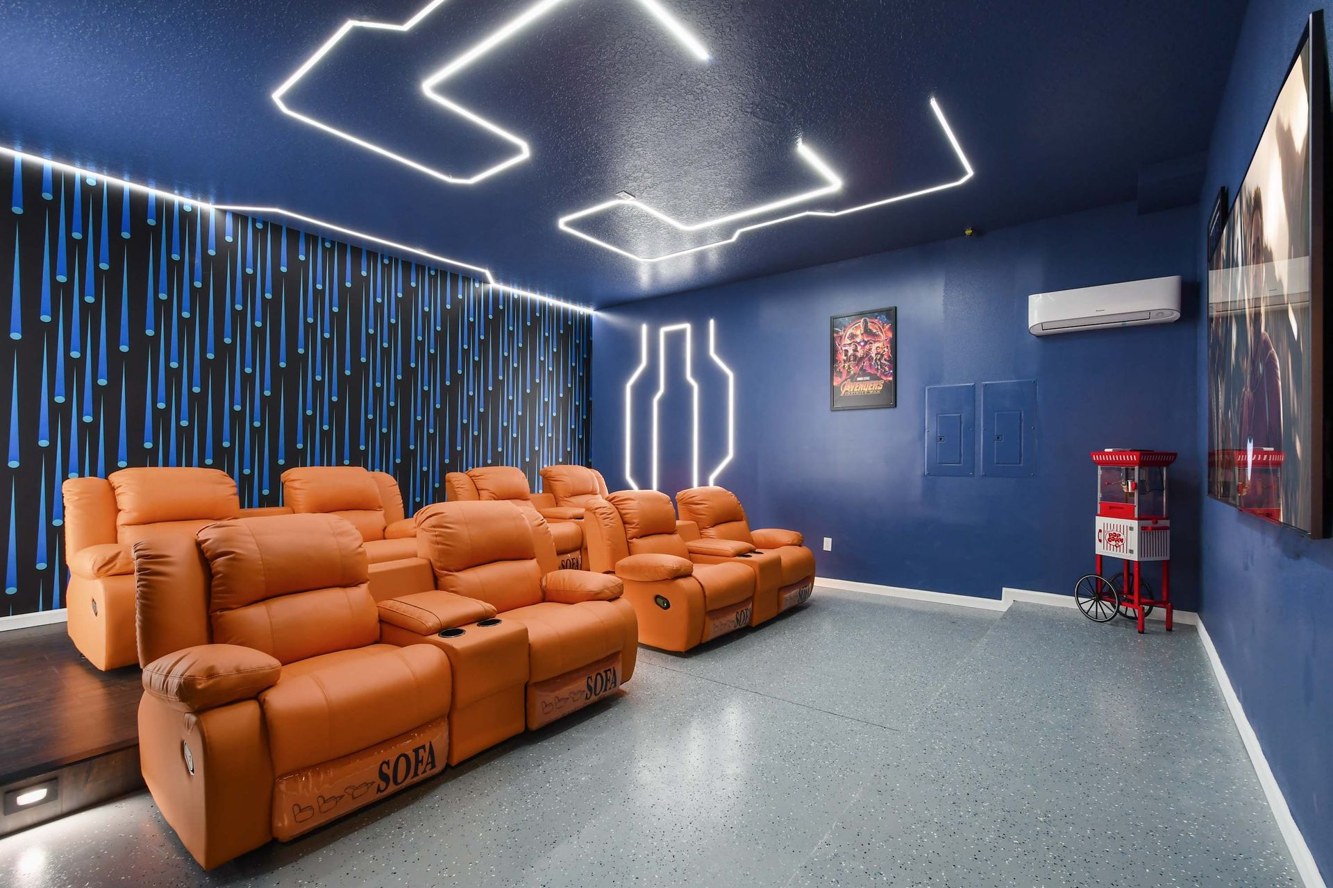 Futuristic home theater with plush recliners, neon lighting, and a popcorn machine.