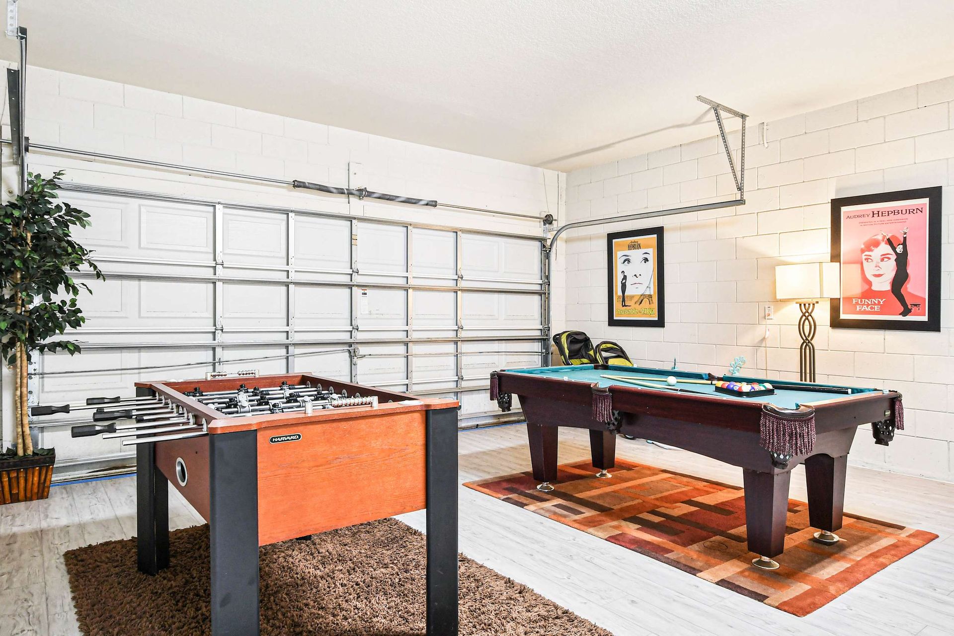 Stylish game room with a pool table, foosball, and classic movie-themed decor.n