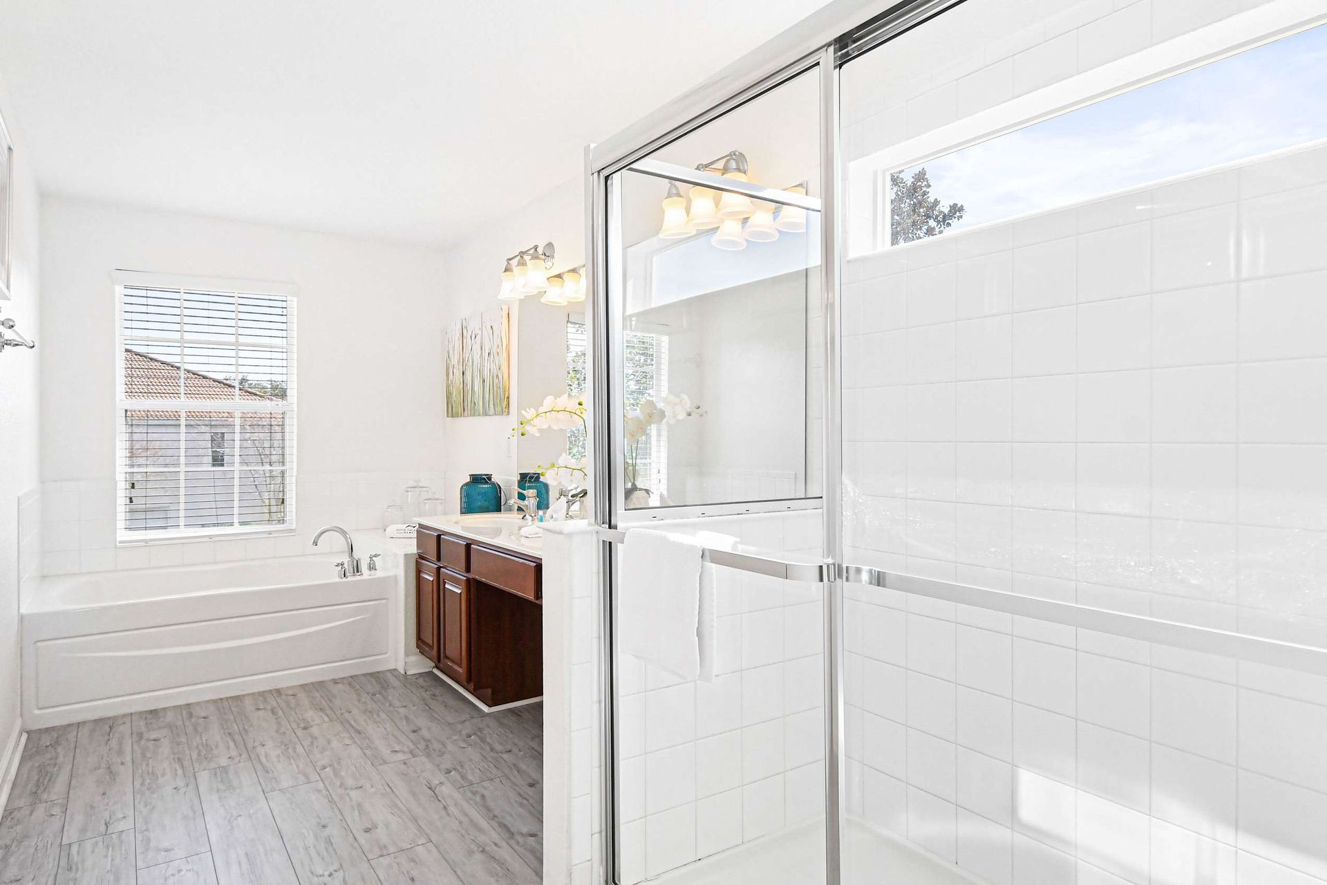Spacious and bright bathroom with a soaking tub, glass shower, and elegant decor.