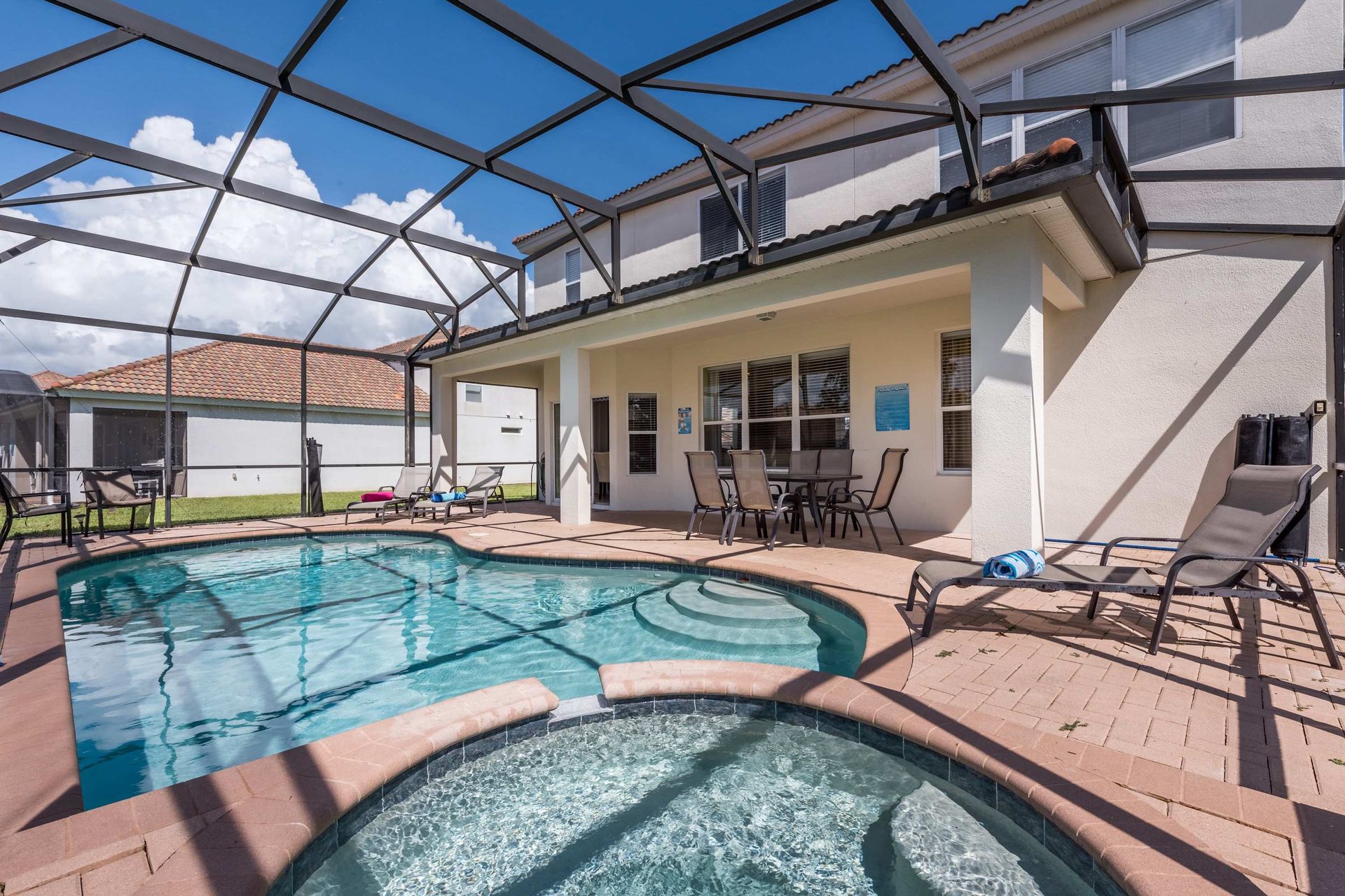 Screened-in private pool with lounge chairs, a spa, and a shaded patio for relaxation.