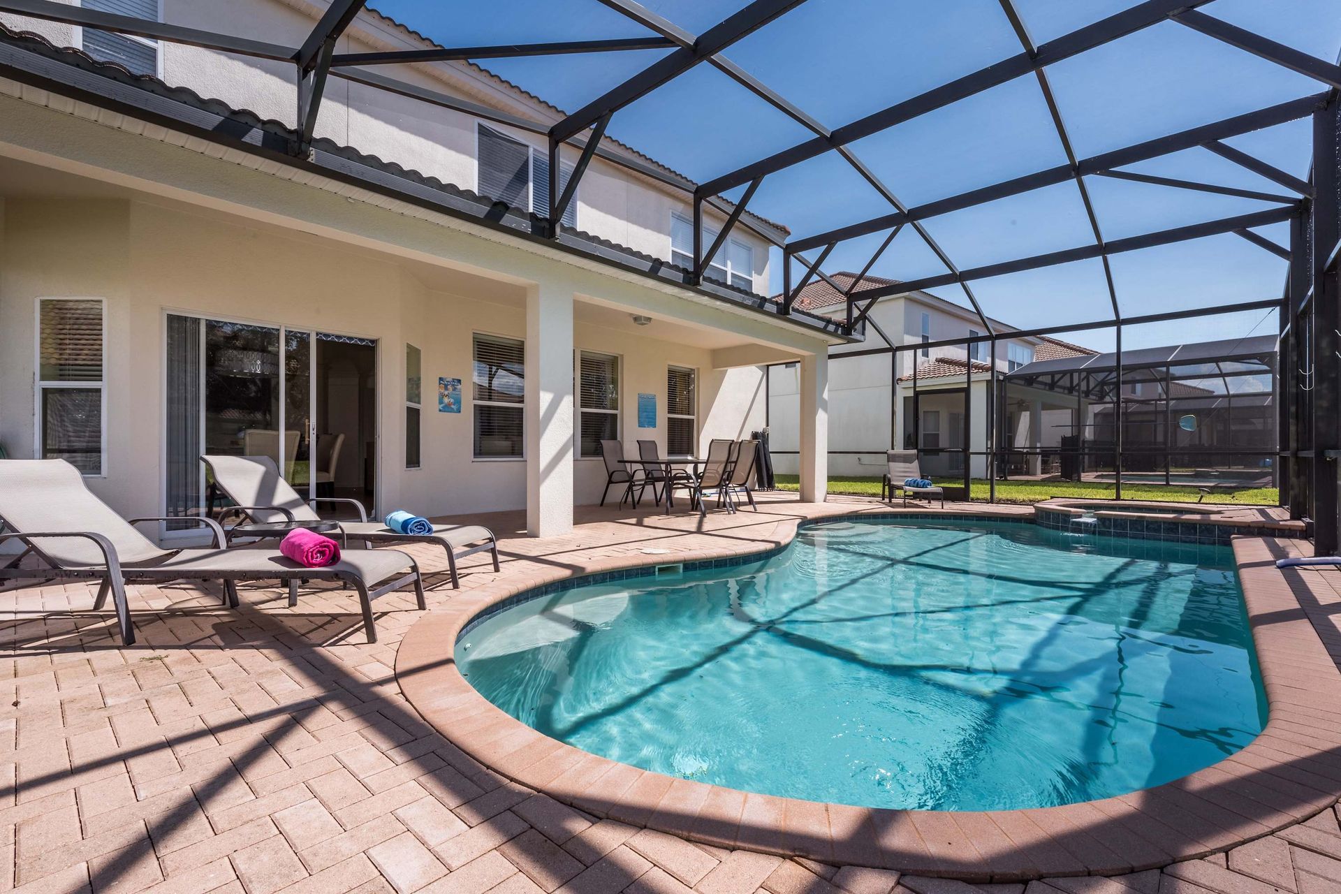 Screened-in private pool with lounge chairs, a spa, and a shaded patio for relaxation.