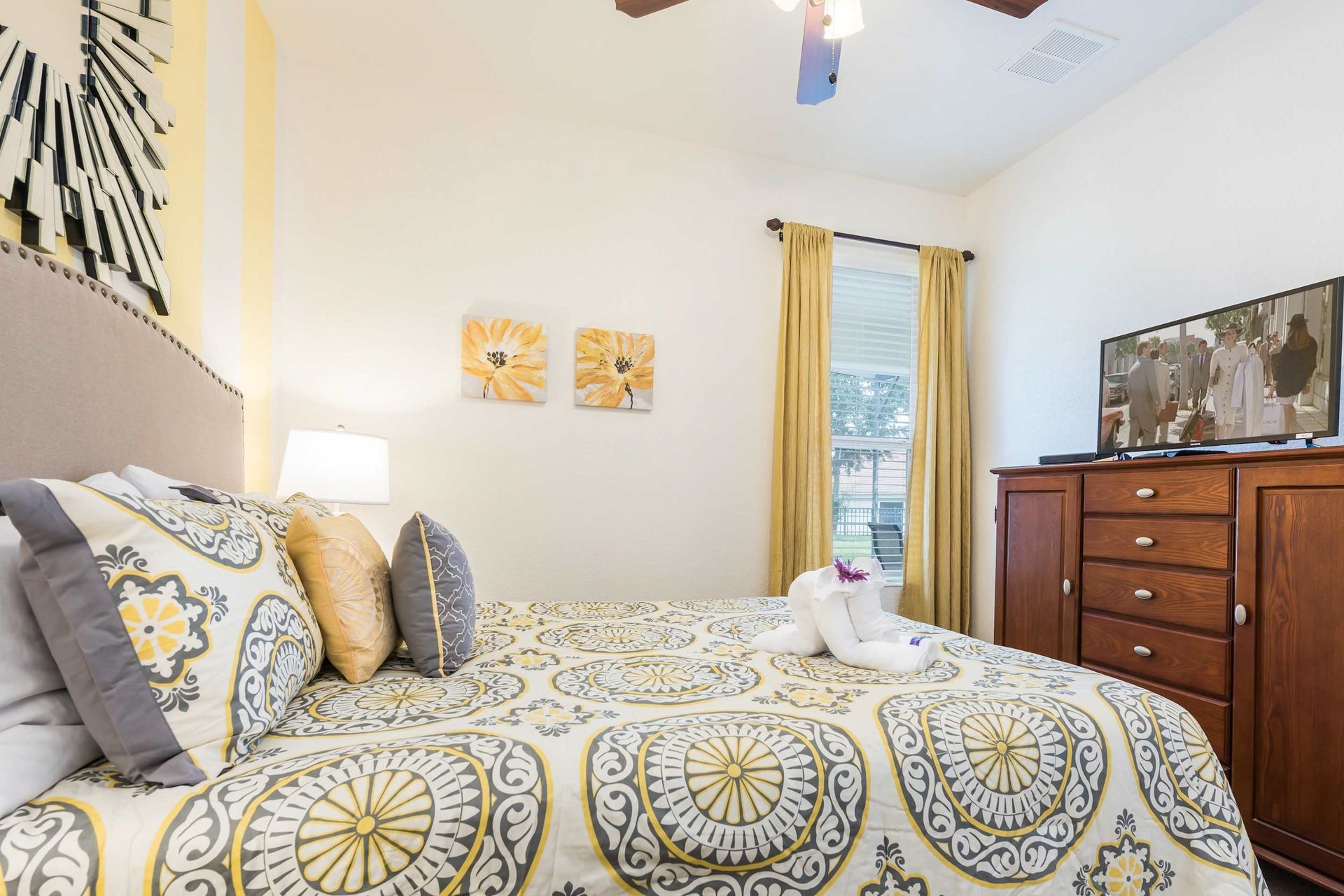 Sunny and stylish bedroom with a cozy bed, warm decor, and a TV for relaxation.