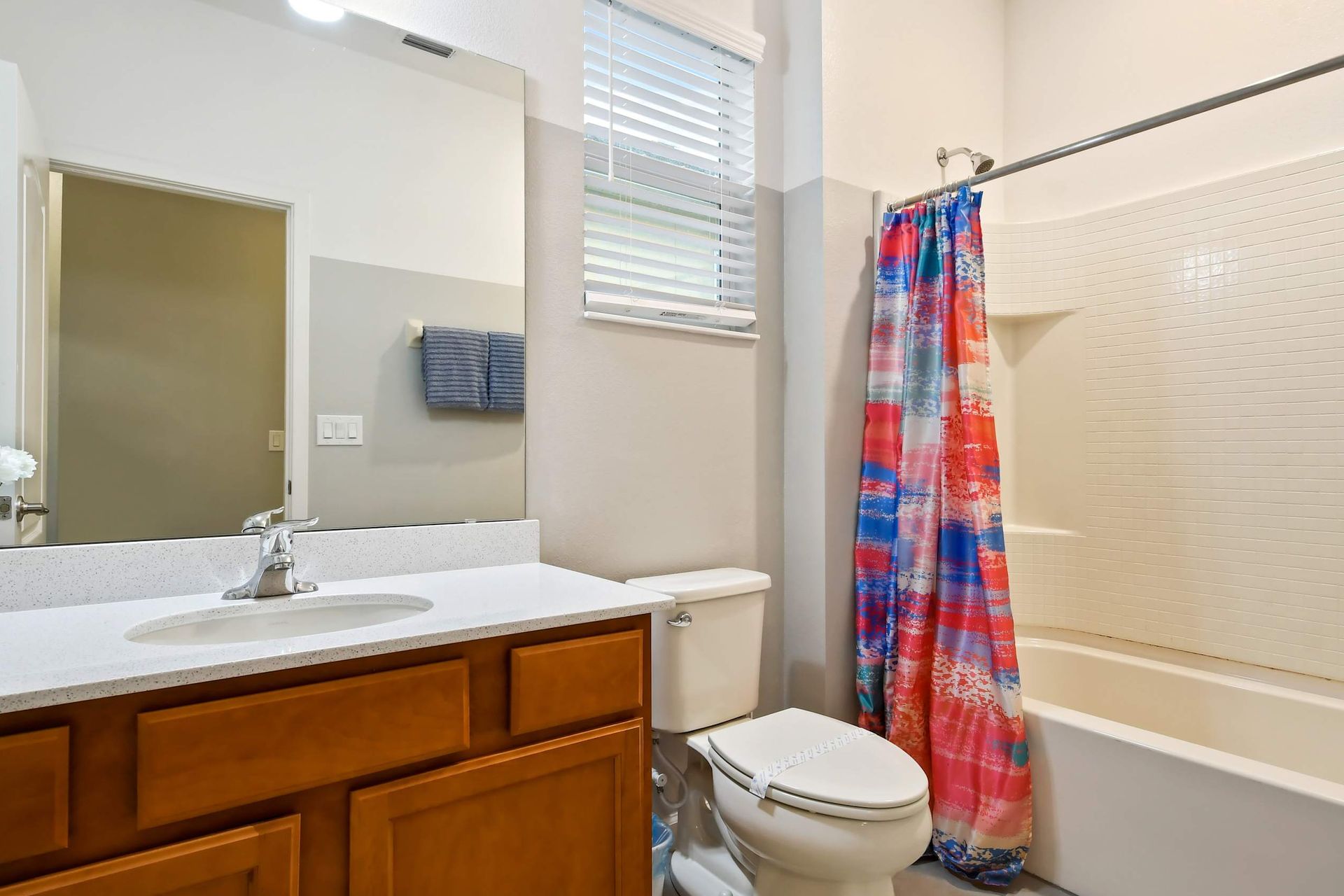 Bright bathroom featuring a vibrant shower curtain, modern vanity, and ample lighting.