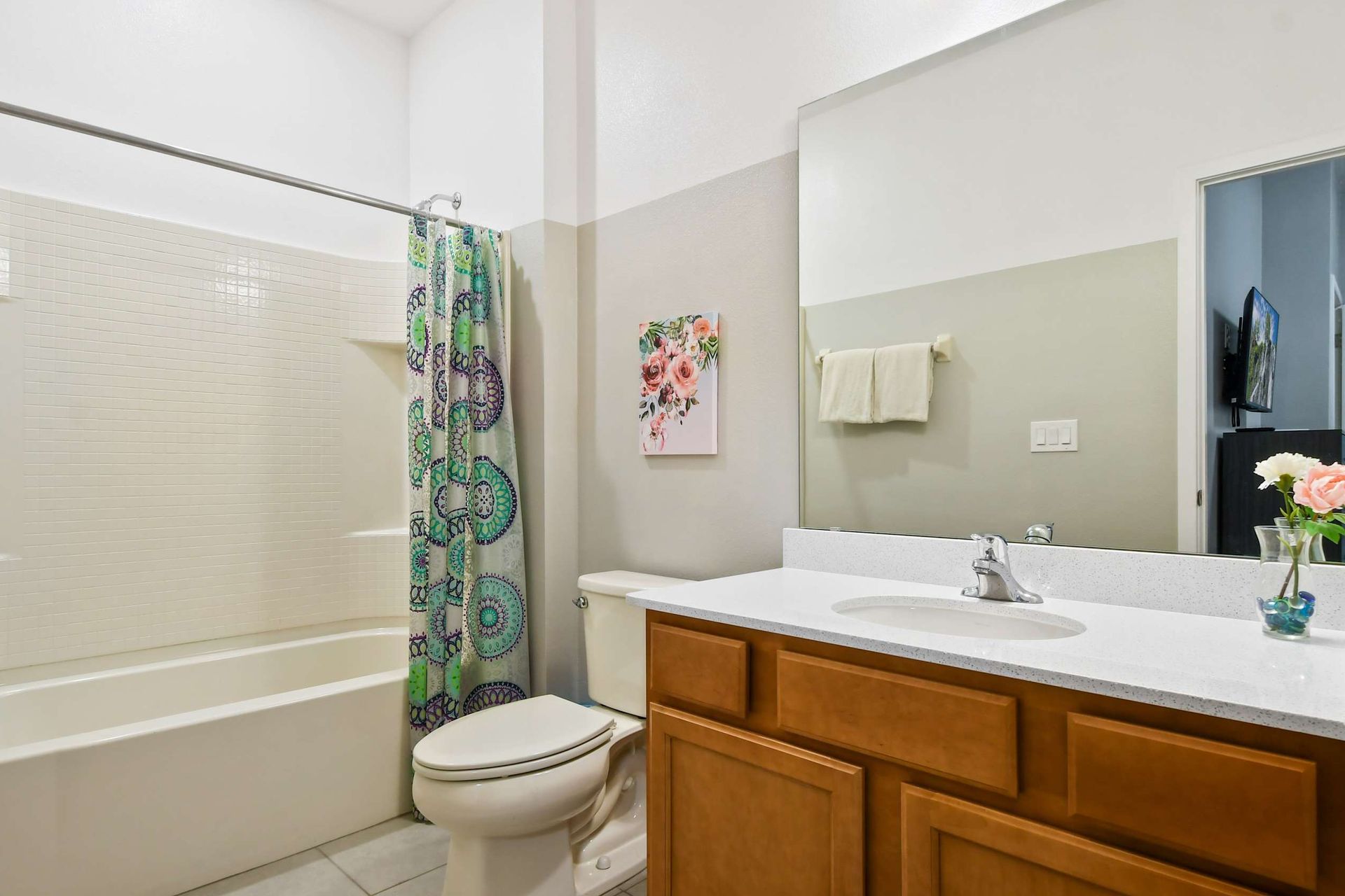 Bright bathroom with a tub-shower combo, cheerful decor, and a modern vanity.