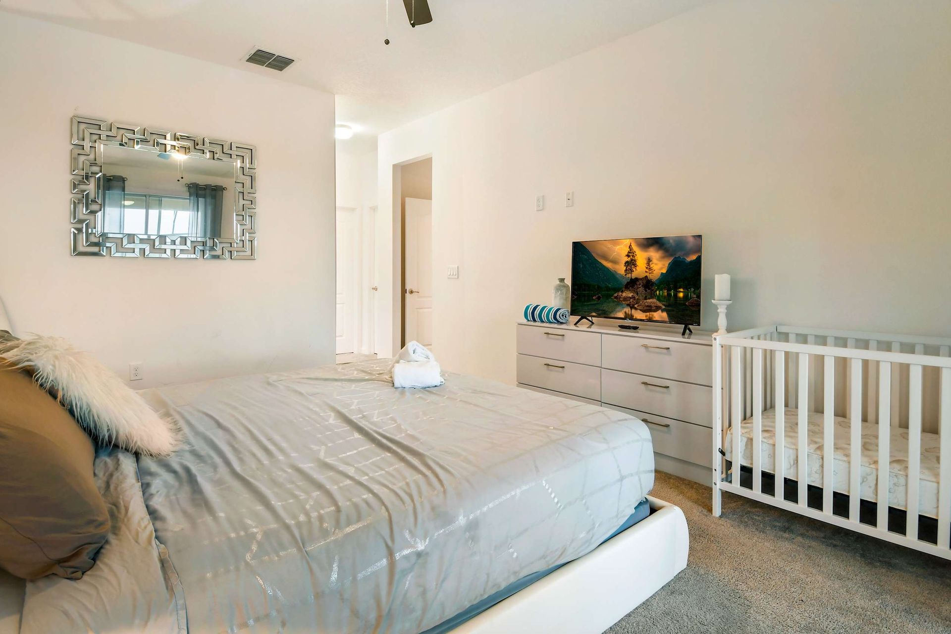 The master bedroom features a luxuriously large king bed with a crib