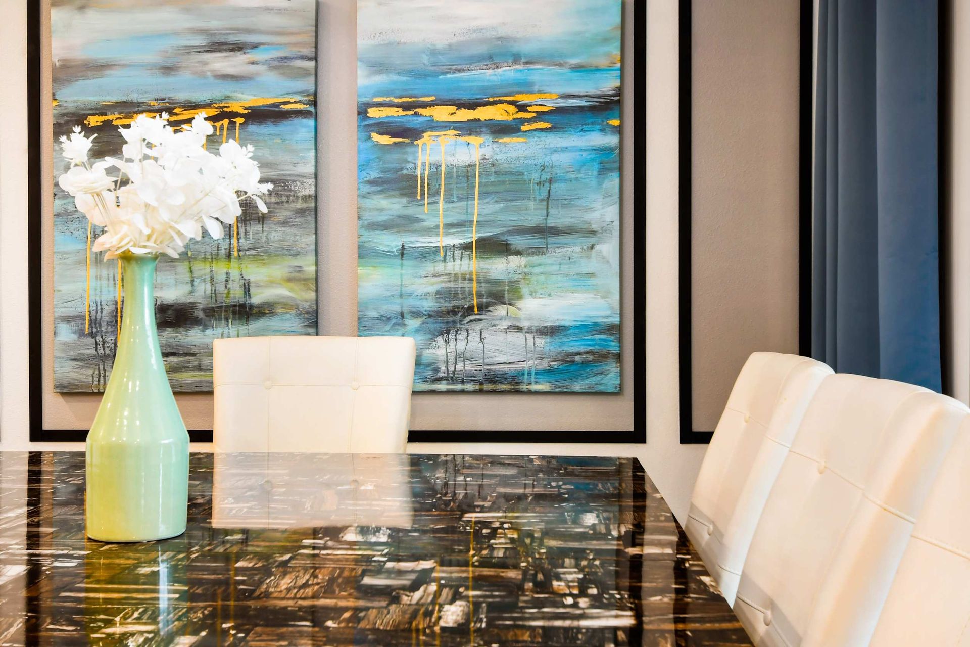 Sophisticated dining space with a sleek marble table, modern art, and elegant decor.