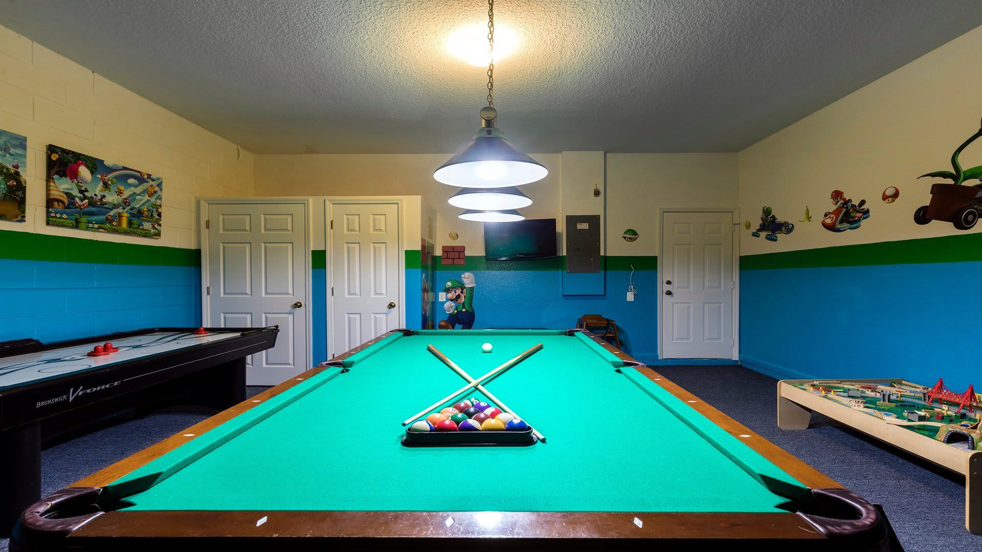 Fun-filled game room with pool, air hockey, kid’s play table, and colorful wall art
