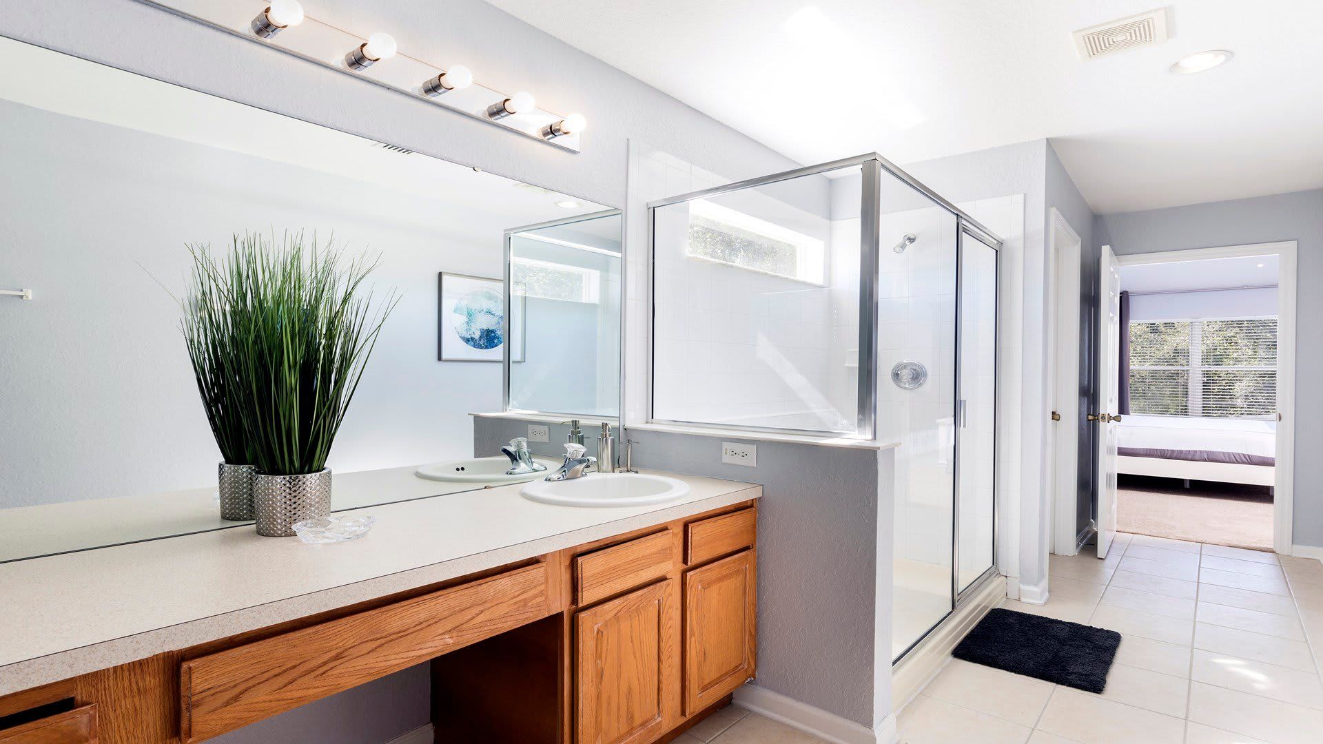 Bright ensuite bathroom with double sinks, glass shower, and modern finishes
