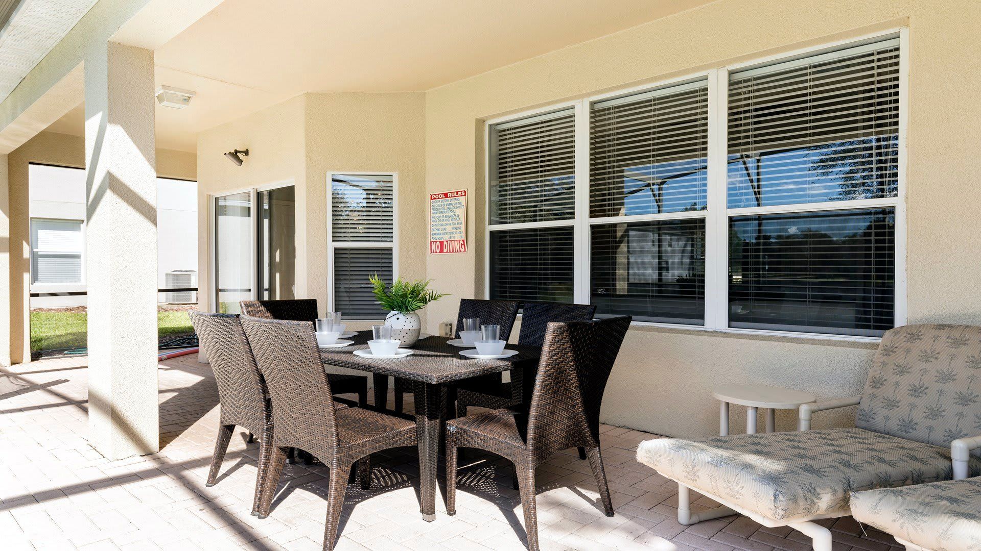 Covered patio with outdoor dining set, lounge chairs, and relaxing poolside vibes
