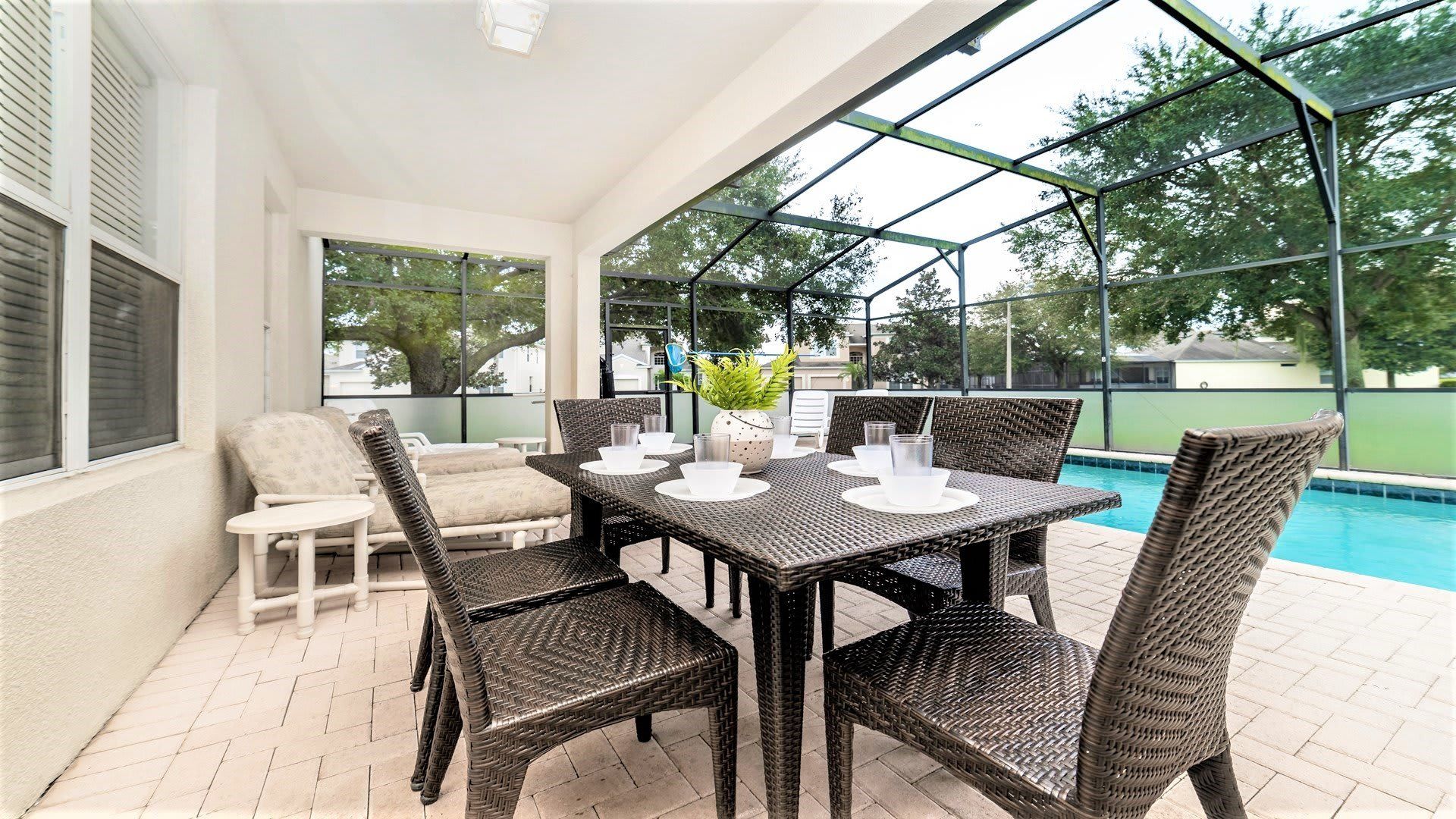 Covered patio with outdoor dining set, lounge chairs, and relaxing poolside vibes
