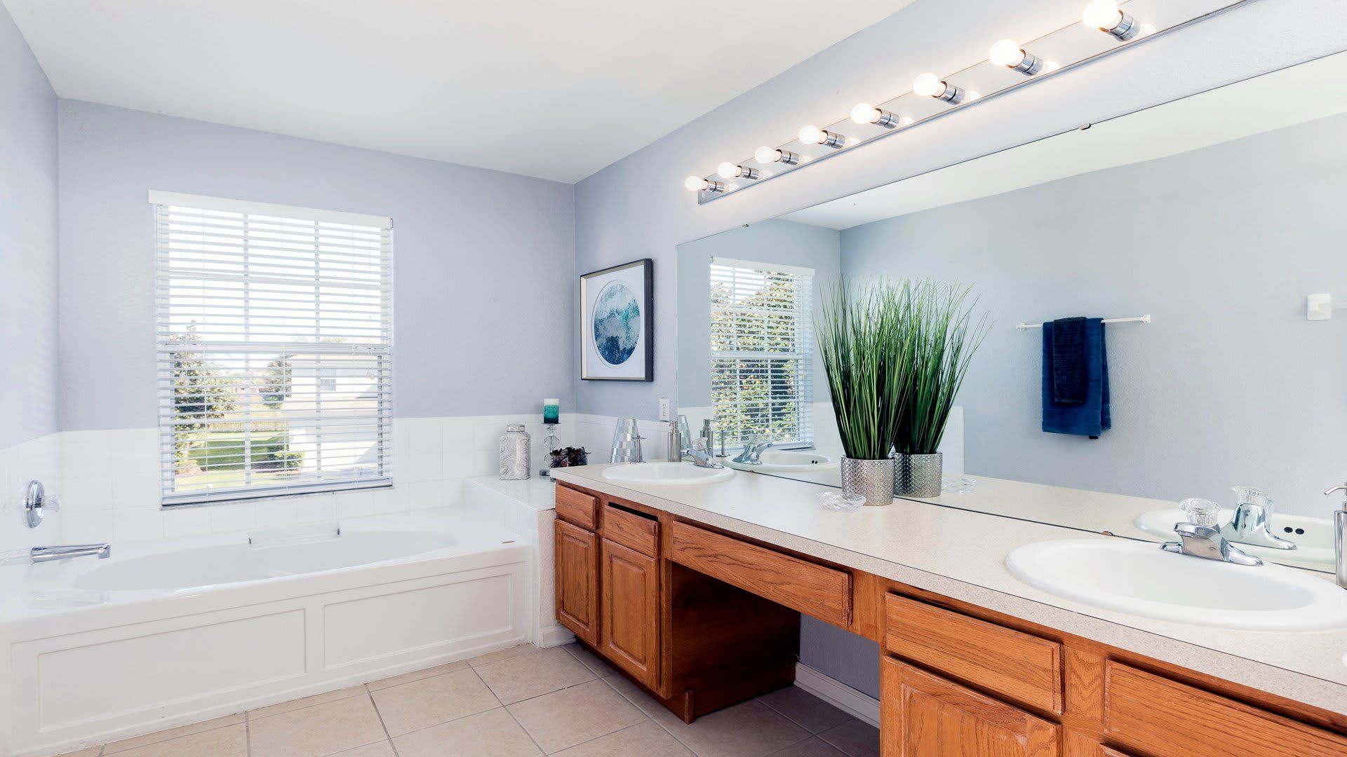 Spacious bathroom with soaking tub, dual sinks, large mirror, and natural light
