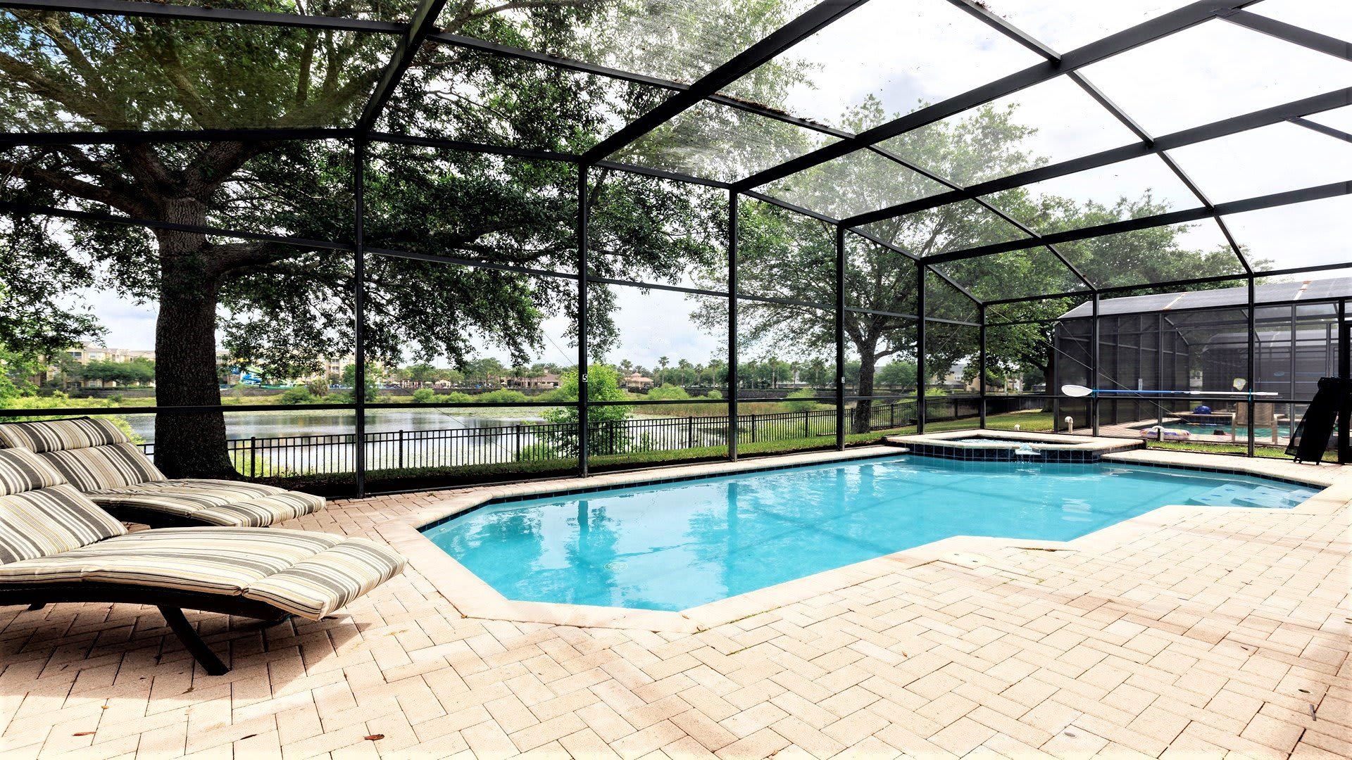 Screened-in private pool with spa, lounge chairs, and stunning lakefront views.