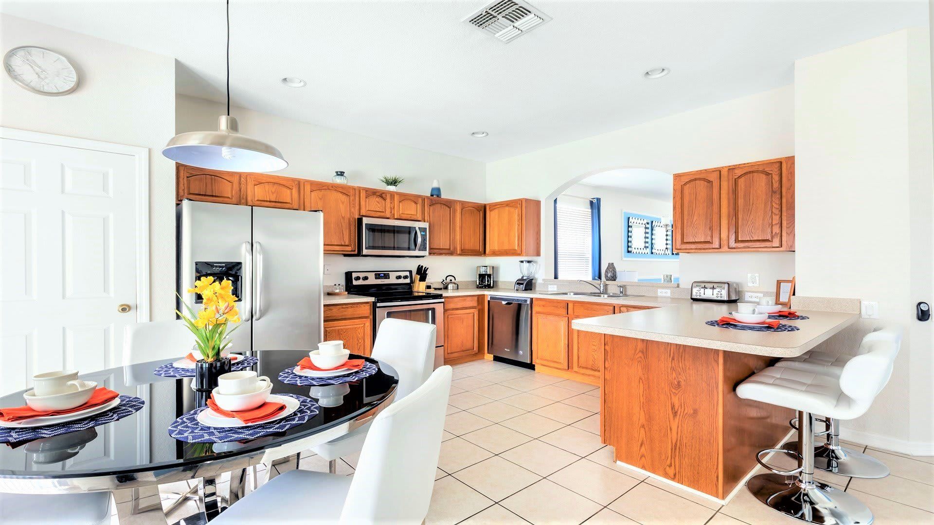 Fully equipped kitchen with stainless steel appliances, warm wood cabinets, and dining.
