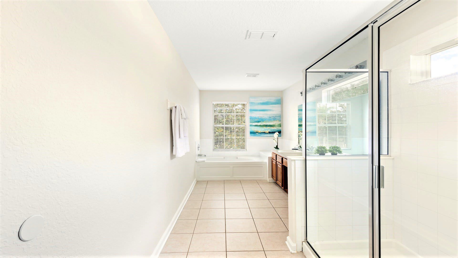Spacious and bright bathroom with a glass shower, soaking tub, and modern decor.