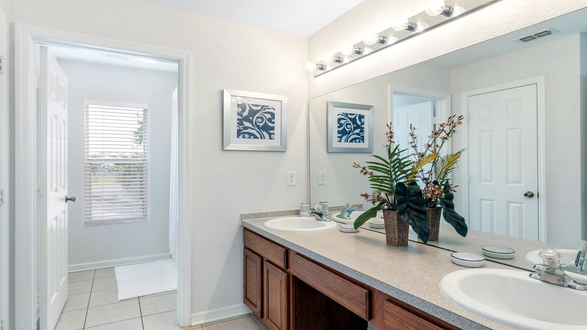 Elegant bathroom with dual sinks, bright lighting, and a modern, refreshing design.