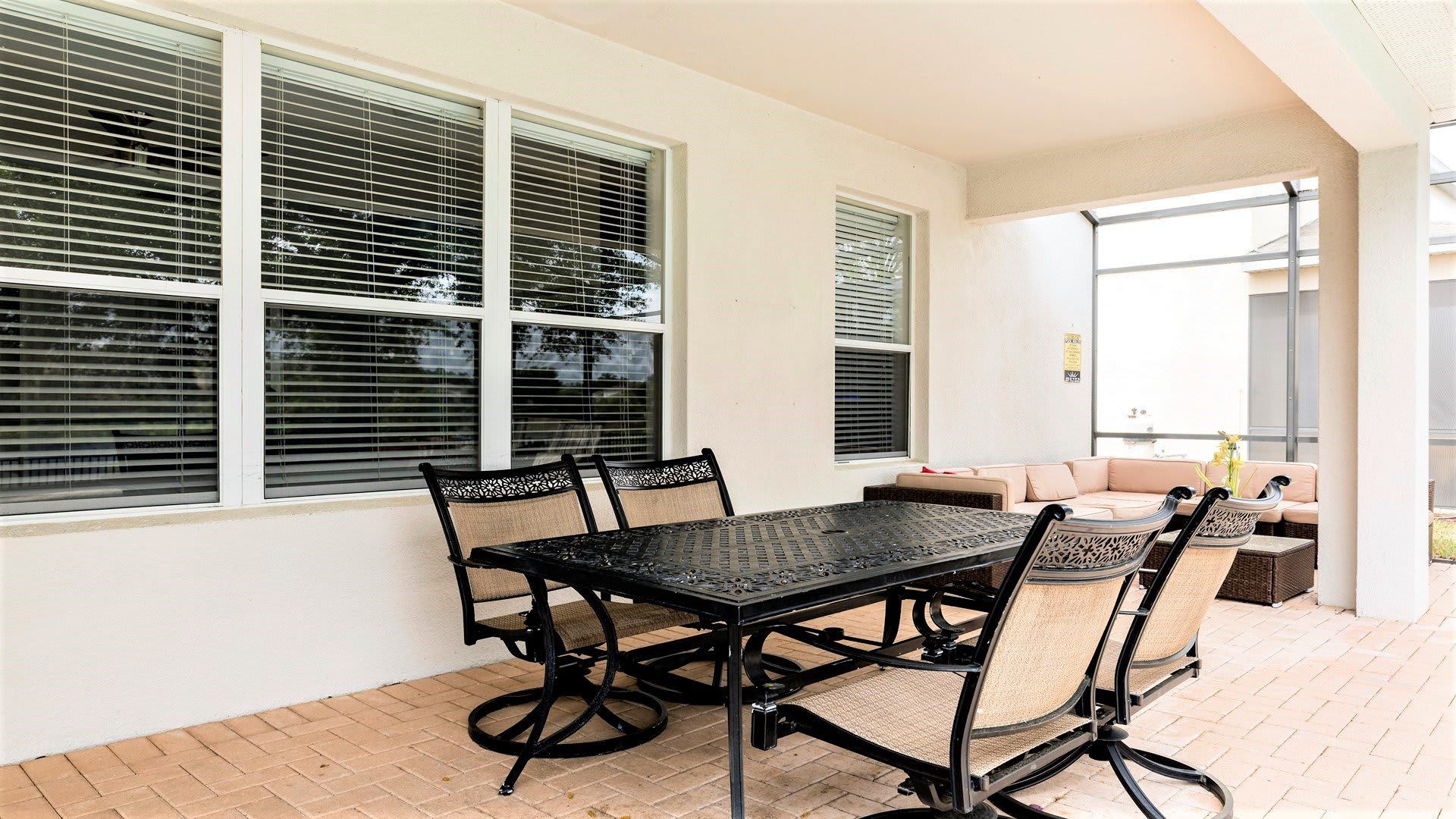 Relaxing covered patio with outdoor dining, cozy seating, and a screened-in view.