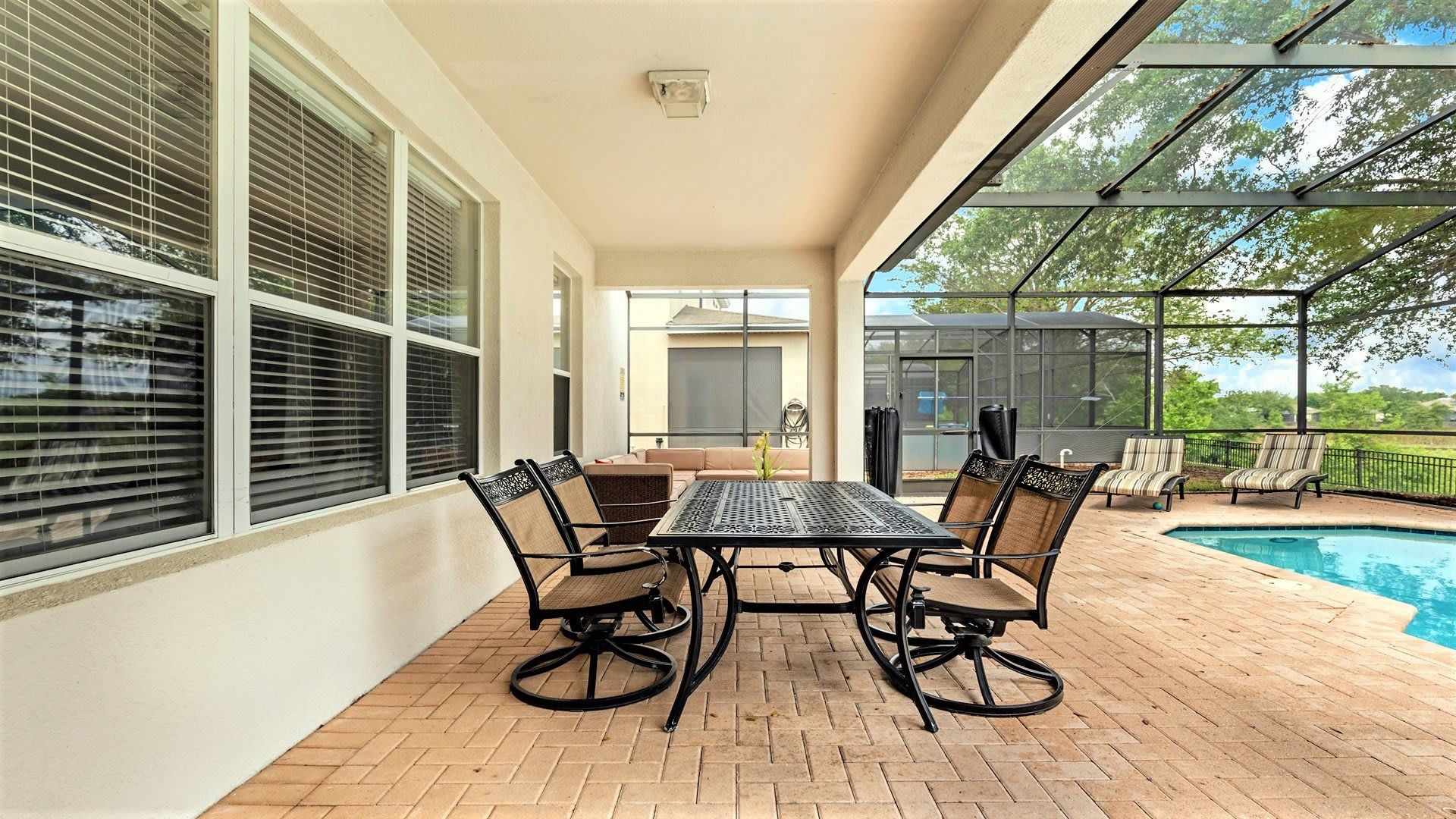 Screened-in patio with outdoor dining, lounge seating, and a private pool with lake views.