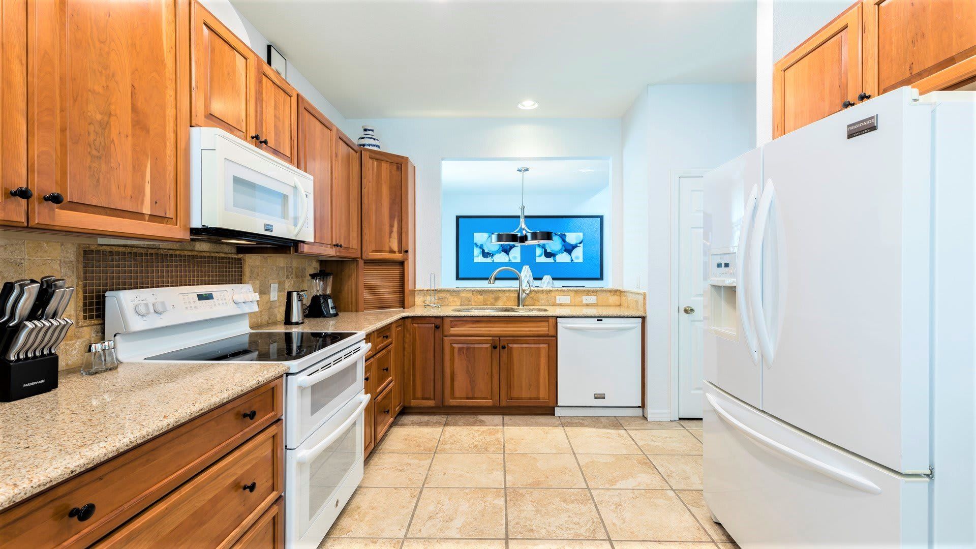 Fully equipped kitchen with warm wood cabinetry, modern appliances, and ample space.