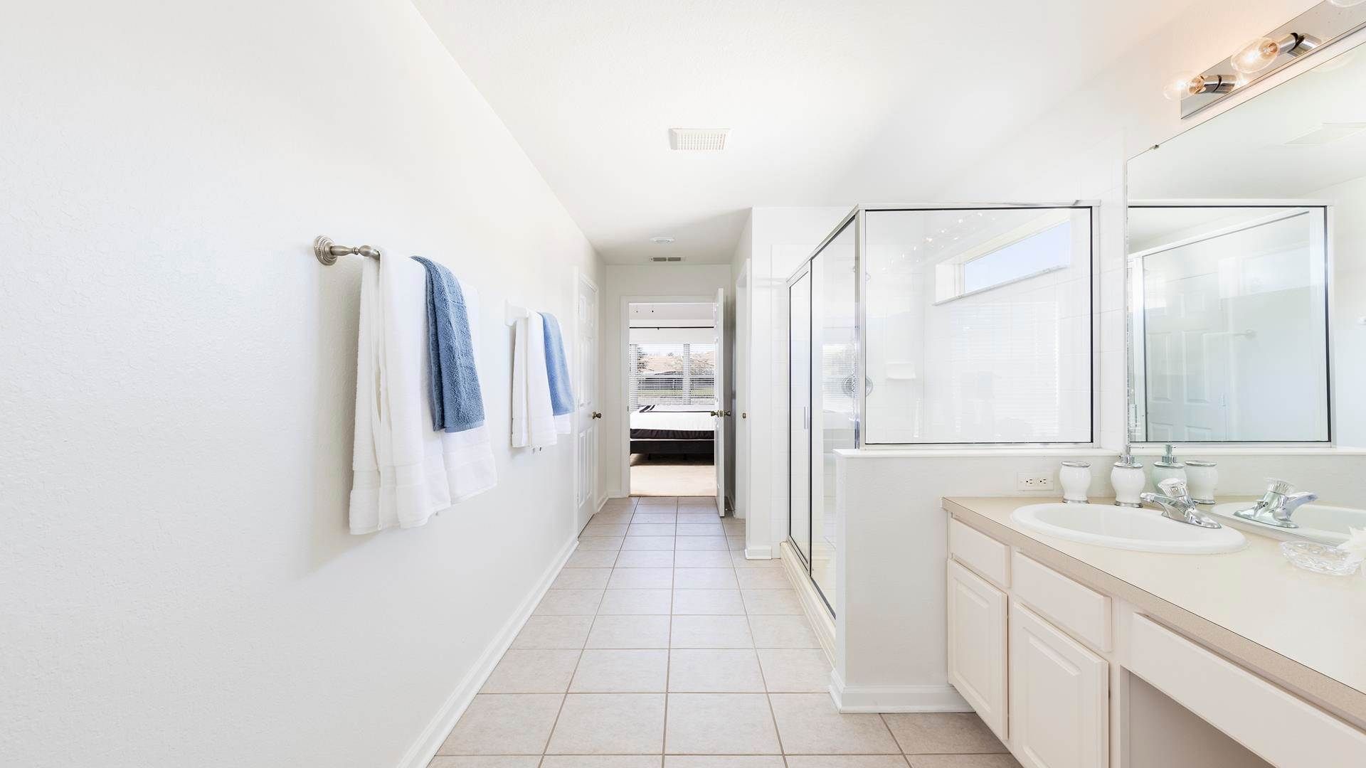 Spacious and bright bathroom with dual sinks, a walk-in shower, and fresh towels.