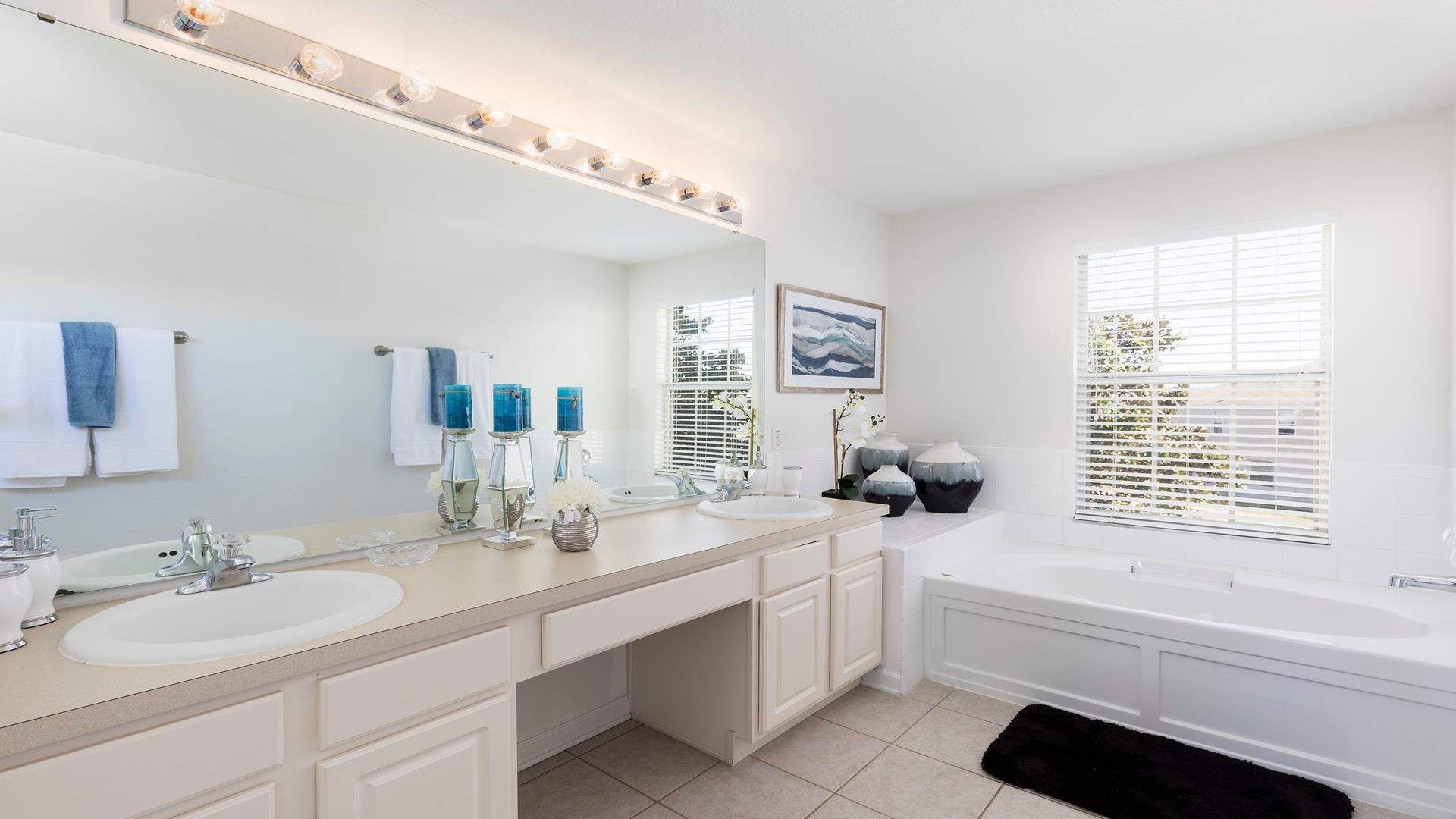 Bright and elegant bathroom with dual sinks, a soaking tub, and stylish decor.
