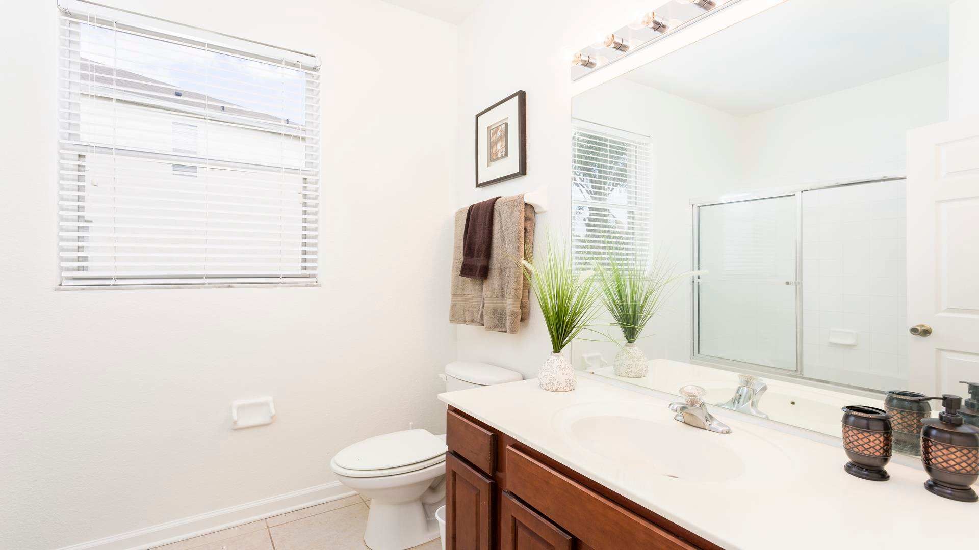 Bright and modern bathroom with a glass-enclosed shower, elegant decor, and fresh linens.